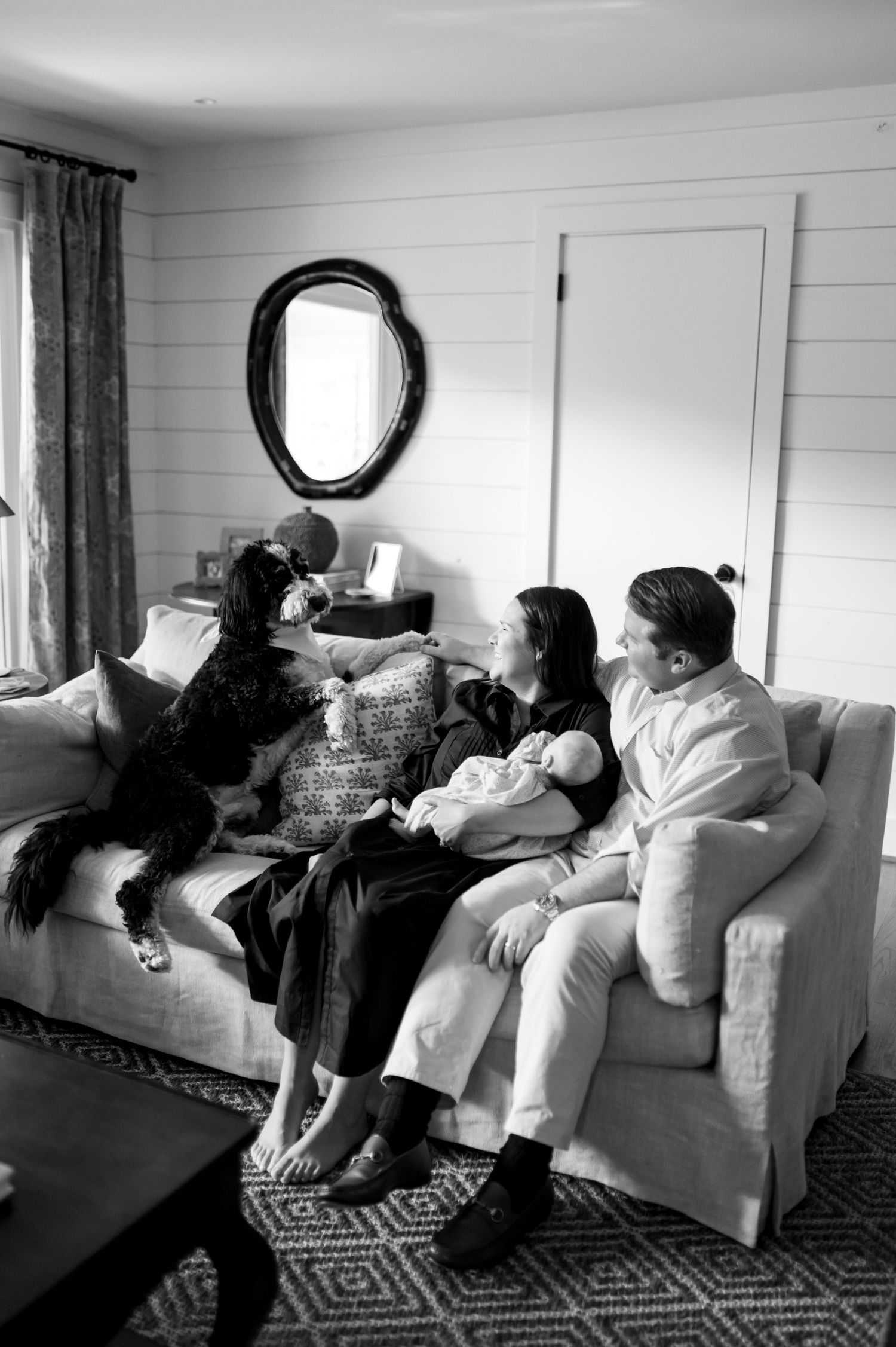 Black and white panoramic sequence showing figures relaxing together on a couch in a living room.
