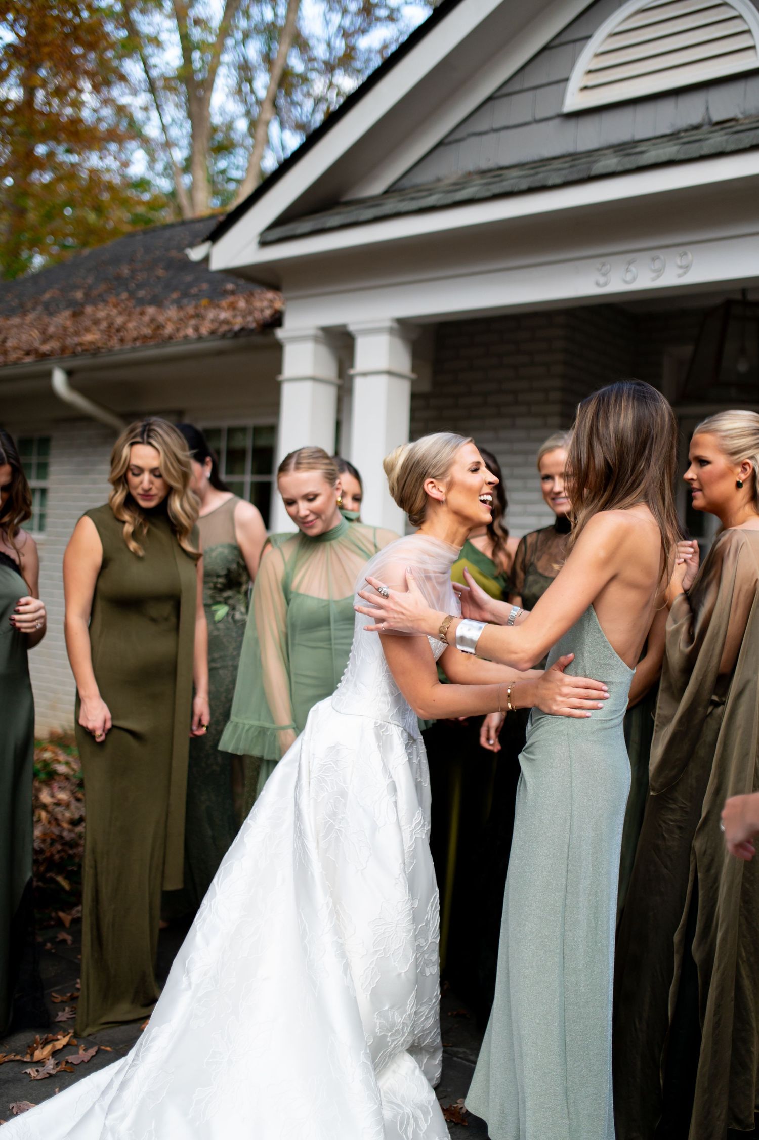 First look reactions with bridesmaids in sage green dresses on a home's front porch.