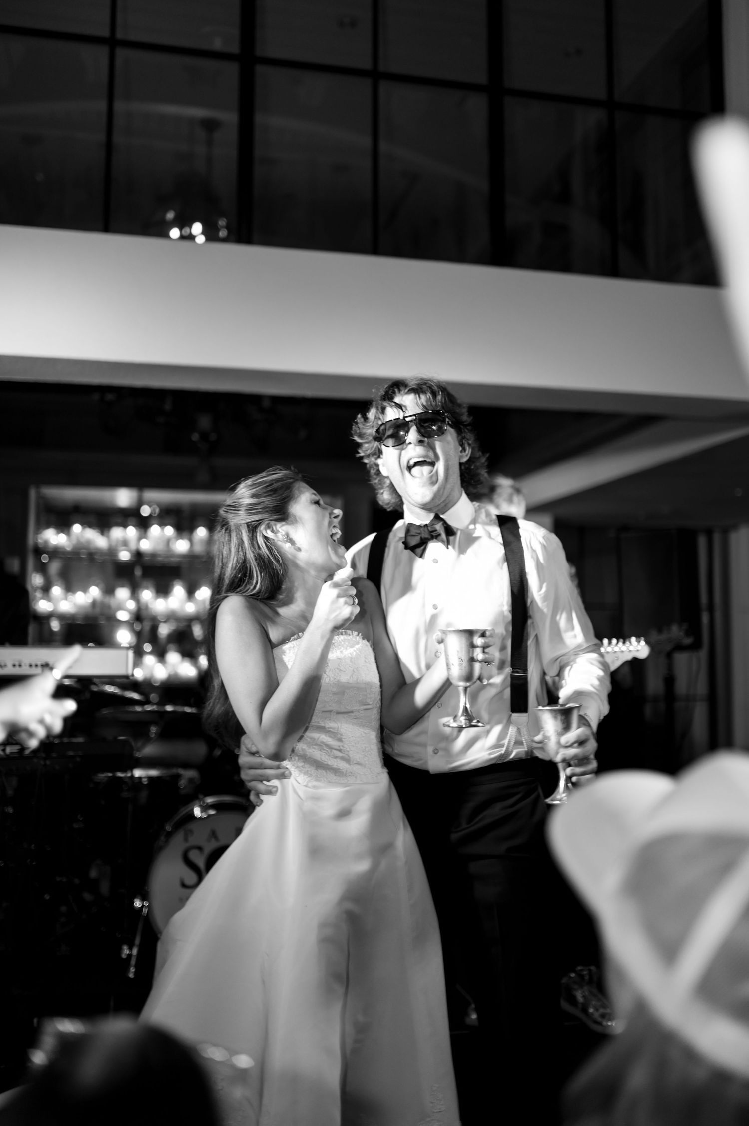 Black and white photo of wedding couple sharing a playful moment on the dance floor.