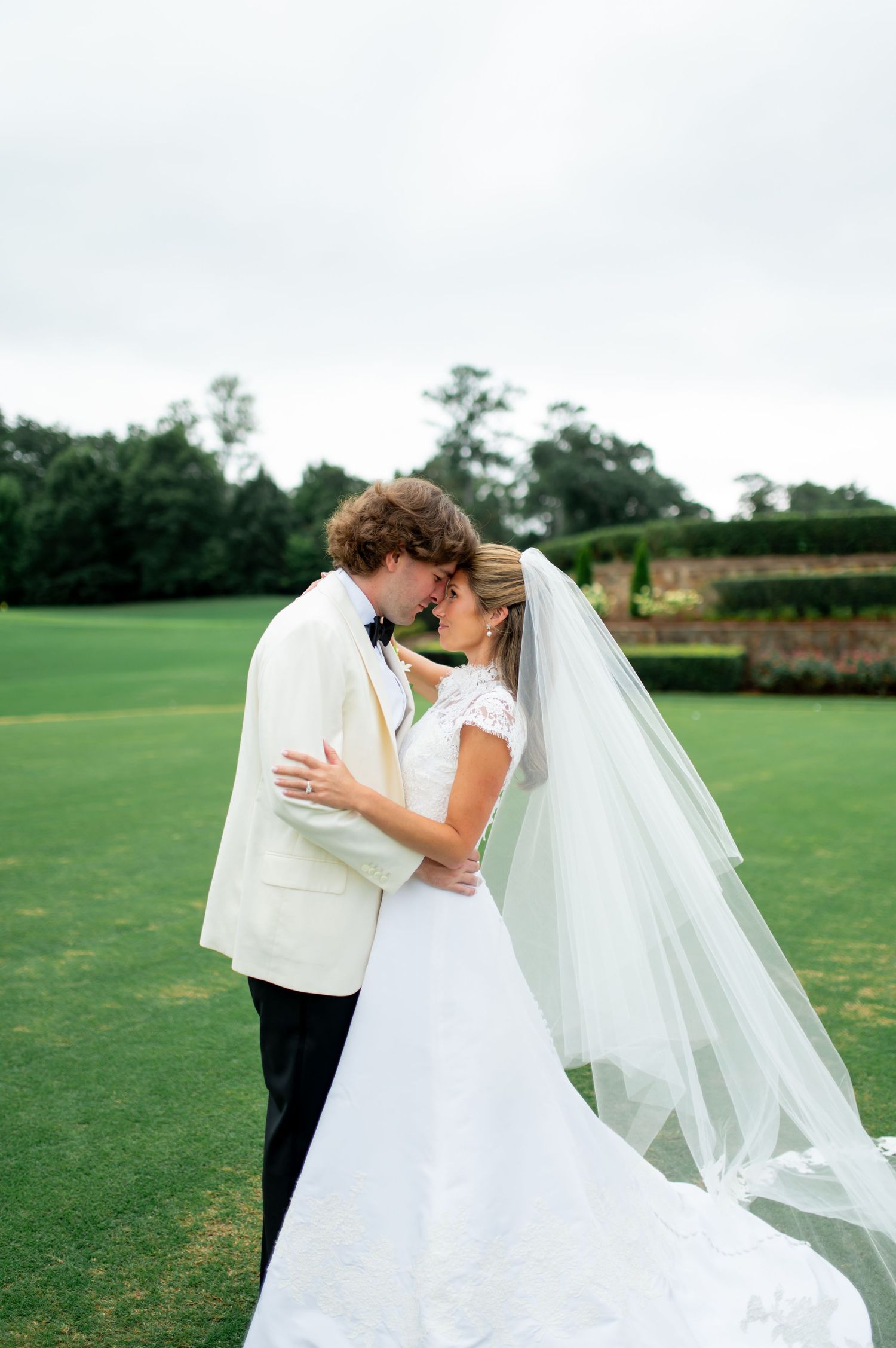 Romantic wedding photos on a golf course with flowing veil and white dress.