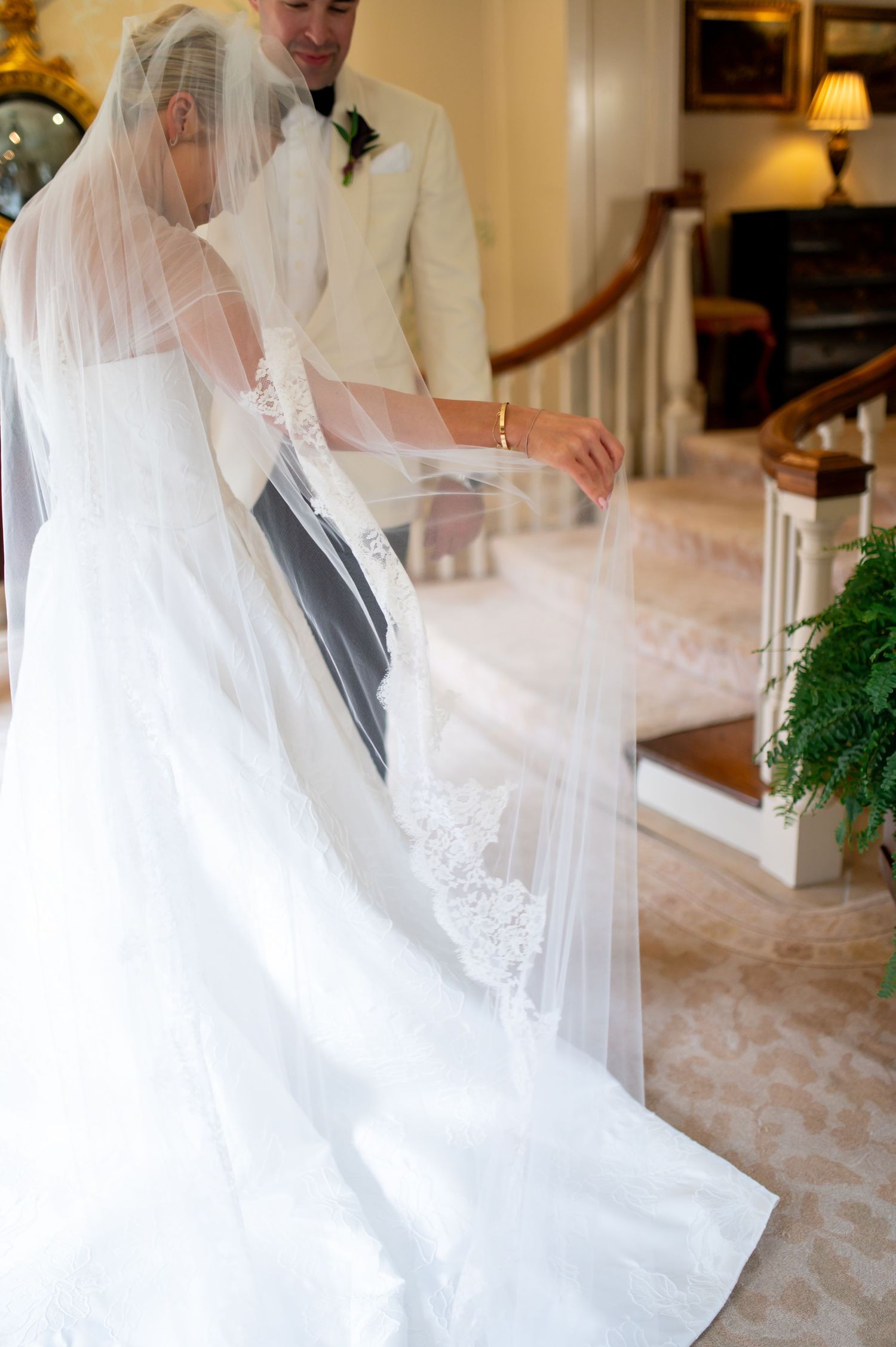 Wedding dress details showing flowing white fabric and delicate veil in a sunlit room.