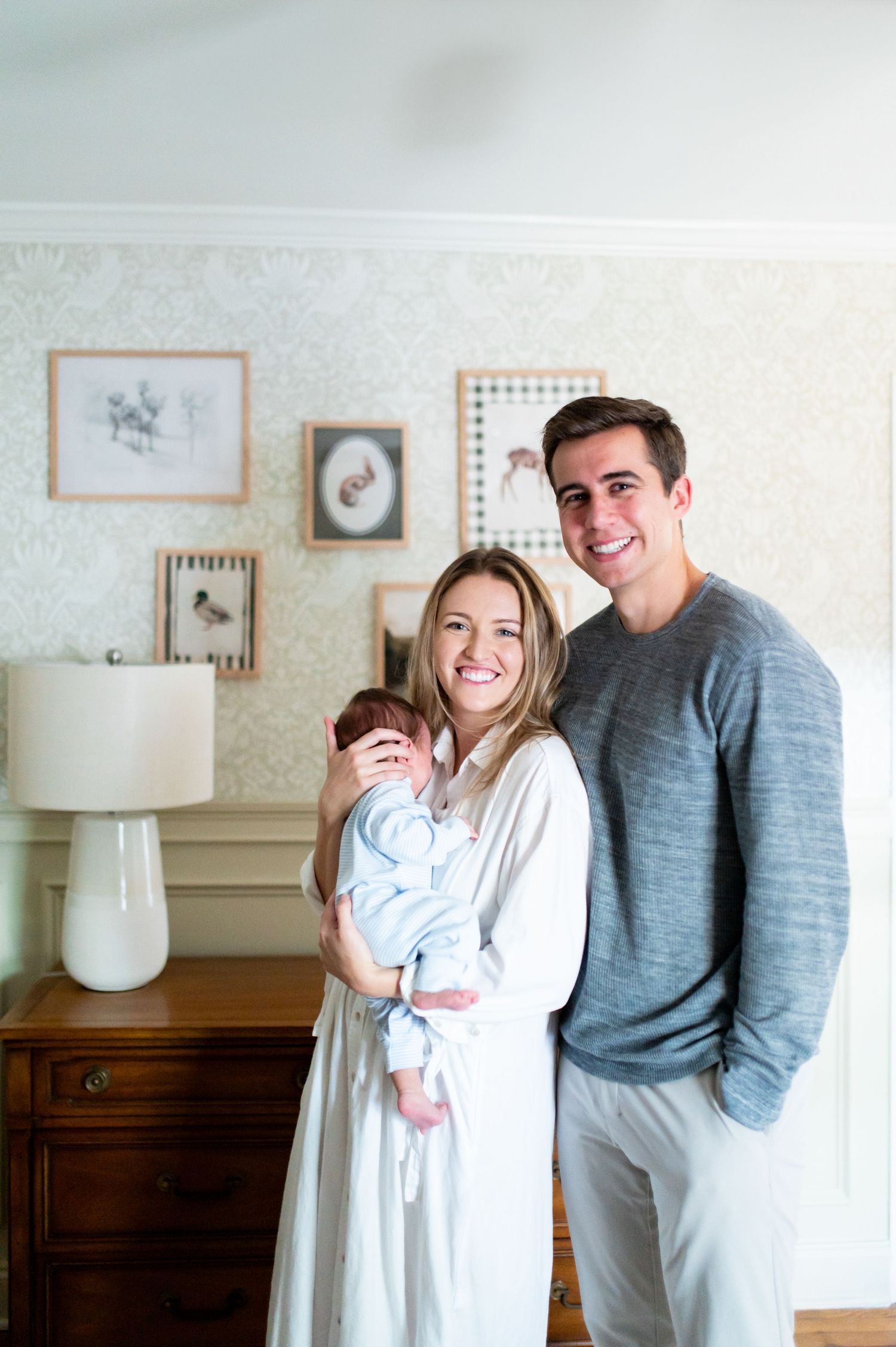A couple shares joyful laughter together while posing in a bright interior room with vintage furniture.