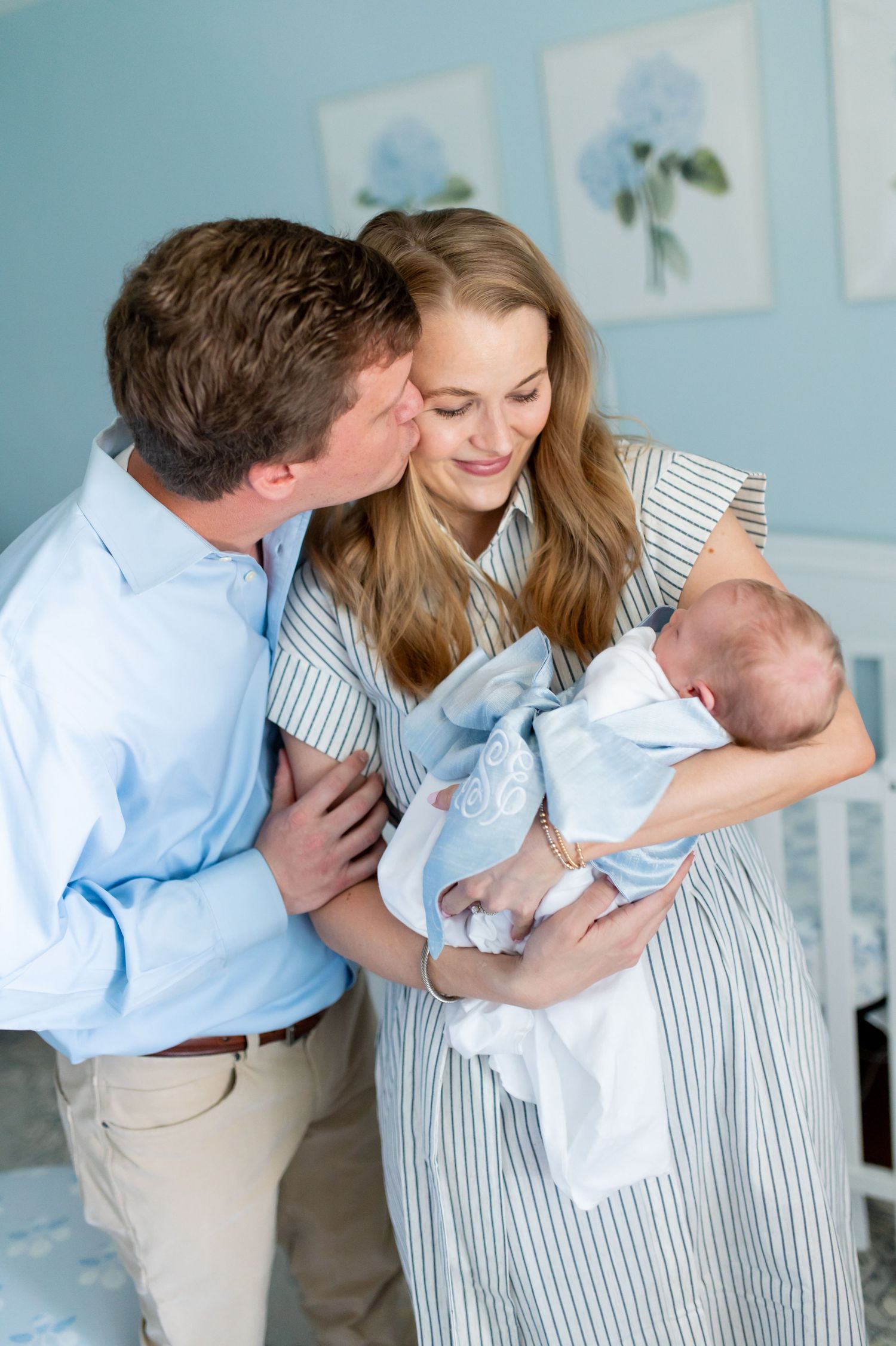Sweet family moments captured in a light blue nursery room with parents and infant.