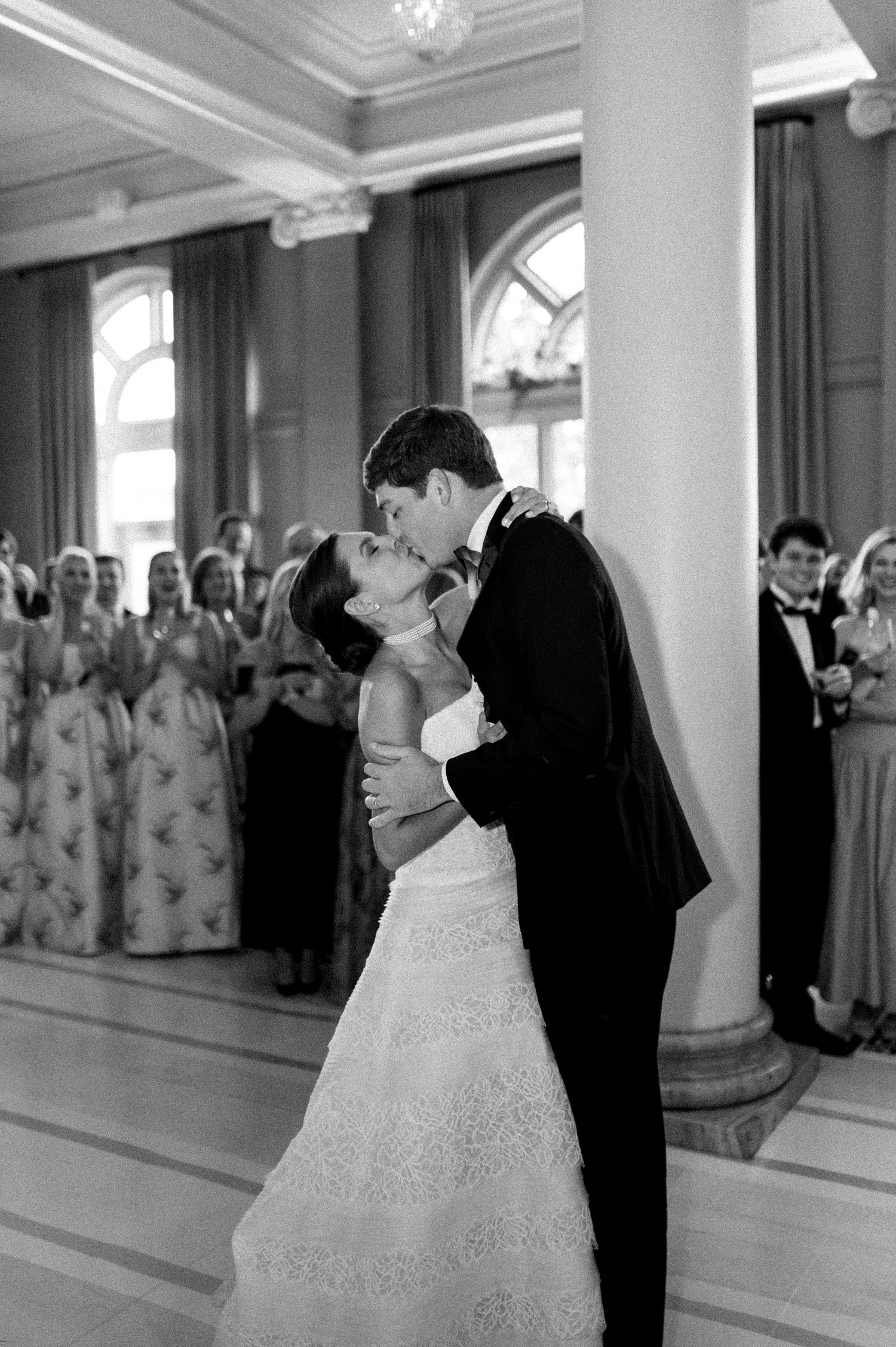 Bride and groom share a romantic first dance kiss in black and white photo at their grand ballroom wedding.