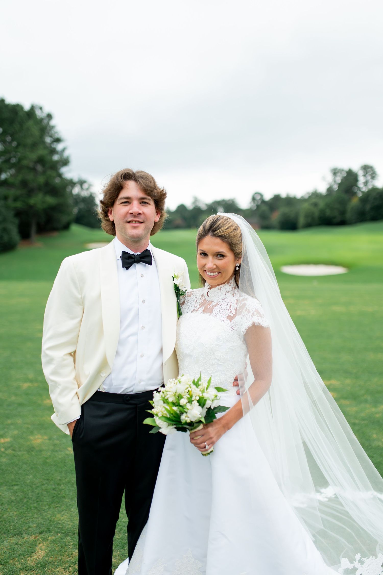 Wedding portrait on a golf course with the couple in white and black formal attire.