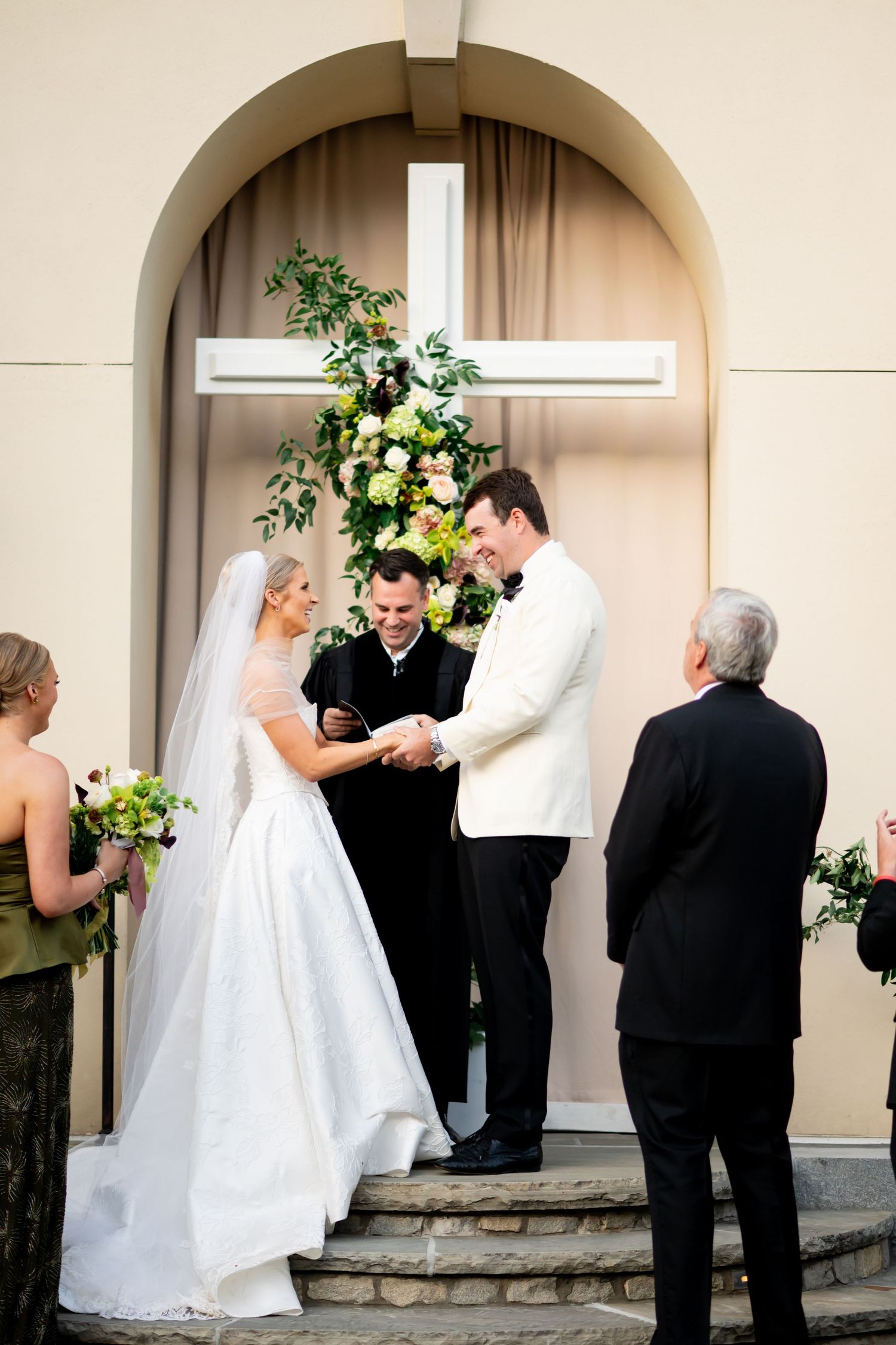 Wedding ceremony taking place under an arched entryway decorated with floral arrangements.