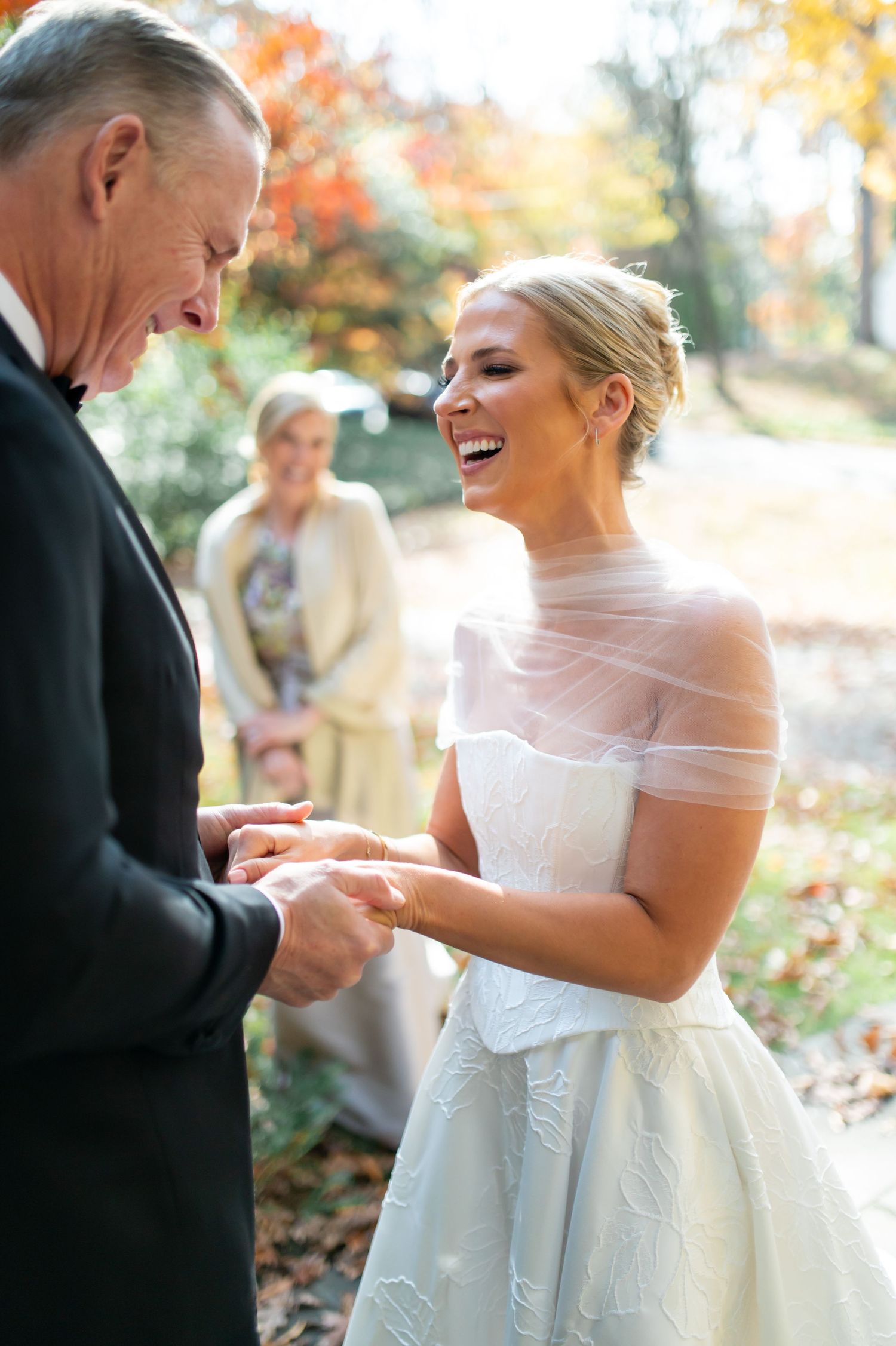 Emotional moment during ring exchange at autumn outdoor wedding ceremony.