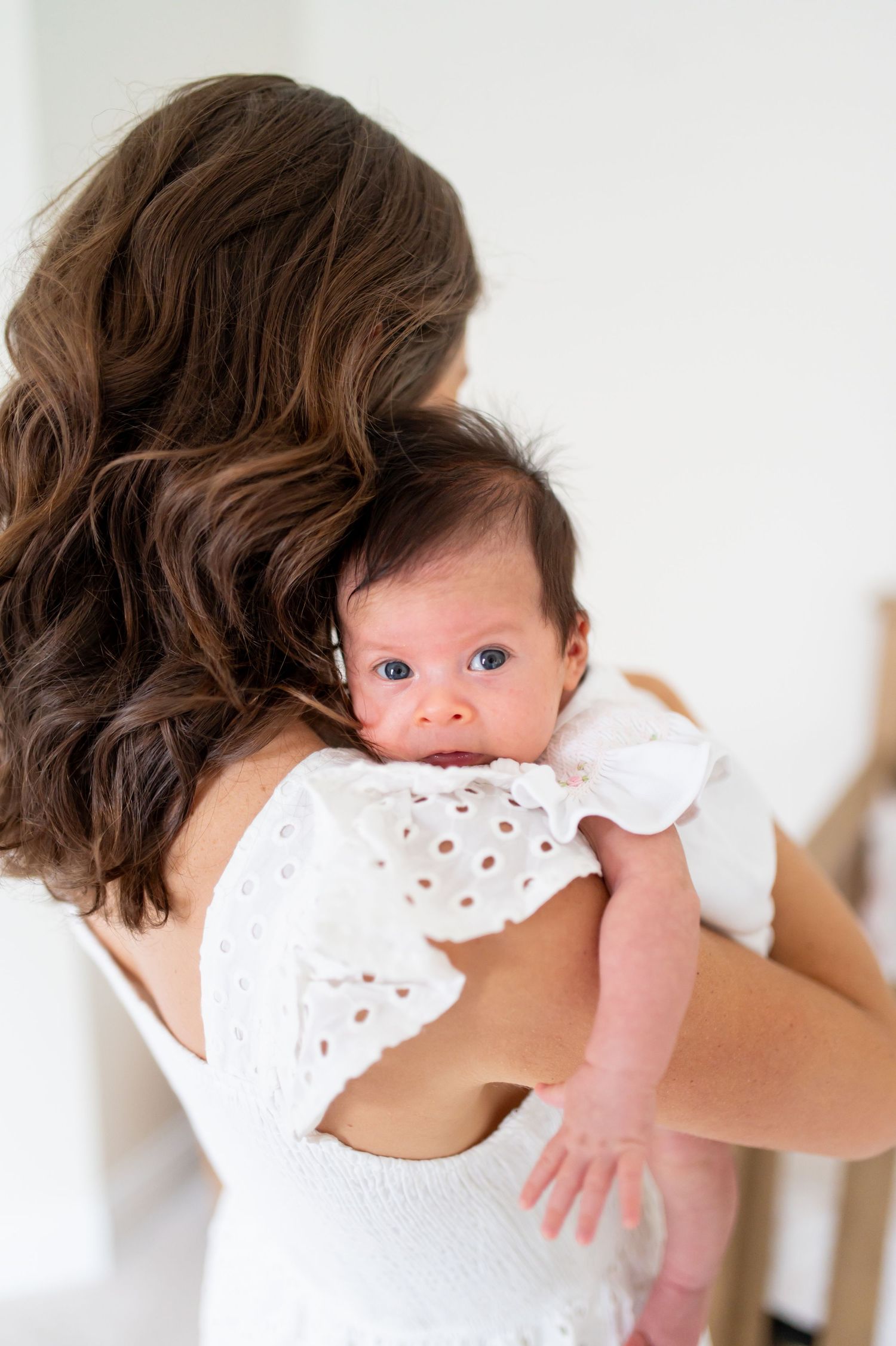 Close-up shots of a baby being held against a white eyelet dress.
