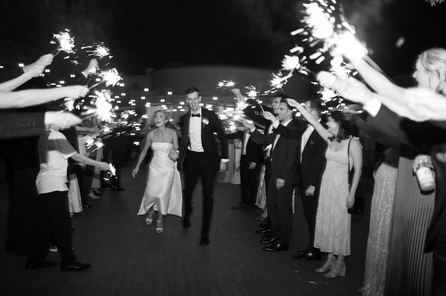 Wedding celebration with sparklers creating magical light trails in black and white photography.
