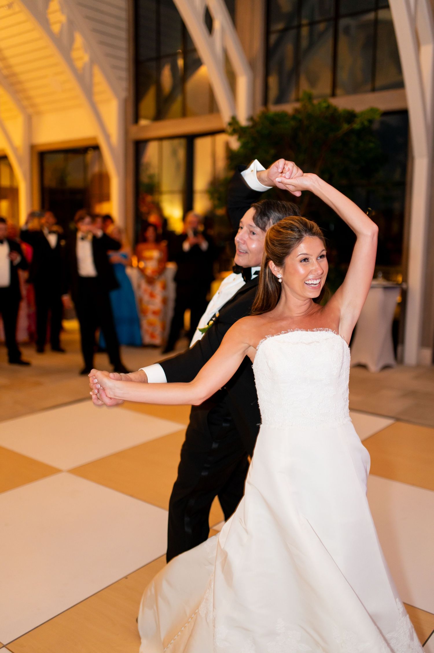 A playful wedding dance moment captured in a bright, airy venue with vaulted ceilings.