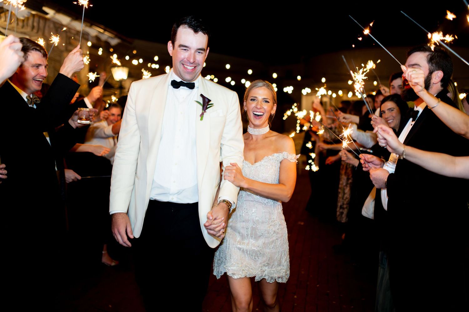 Nighttime wedding celebration with string lights and dancing guests.