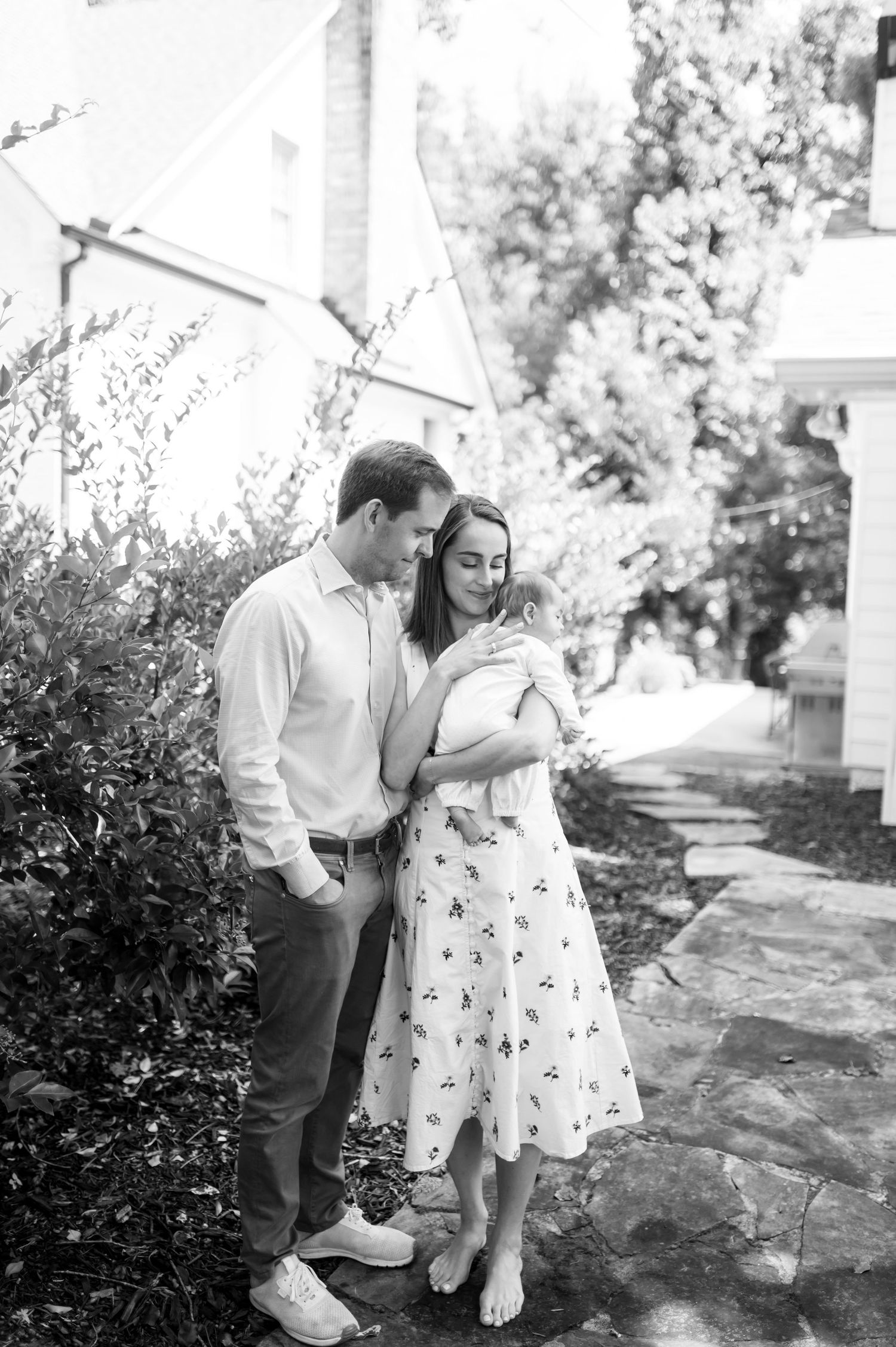A couple shares tender moments with their baby outdoors on a stone pathway.