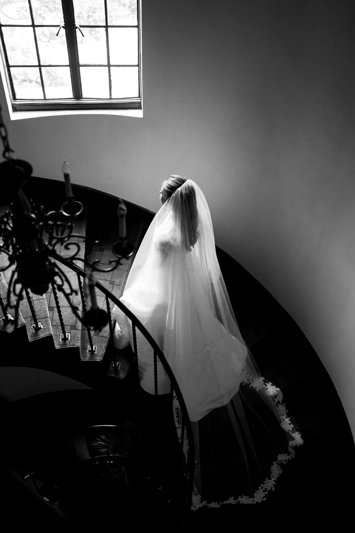 Dramatic black and white silhouette of a wedding dress against window light.