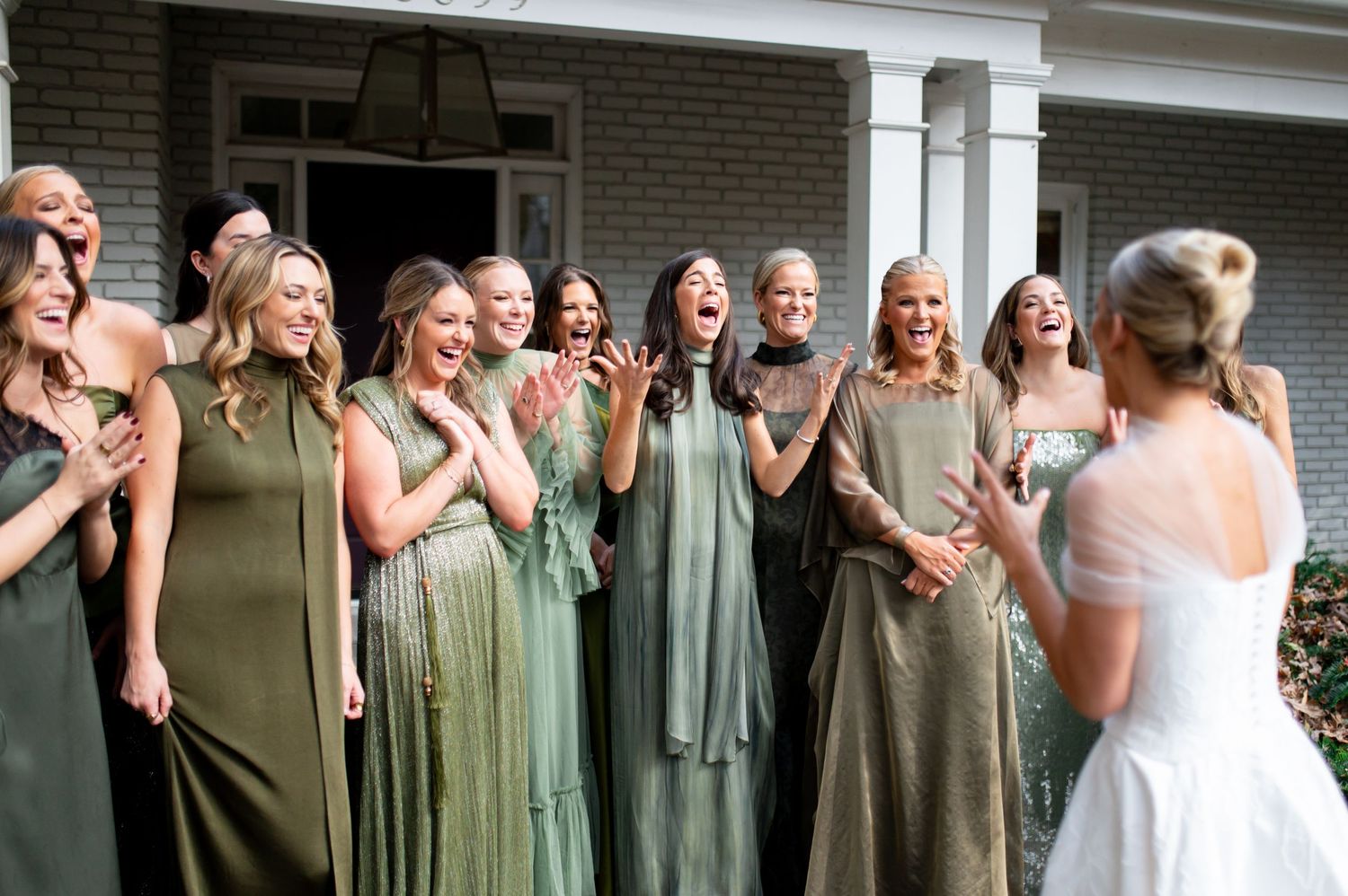 Wedding party in olive green dresses reacting with joy during a first look reveal.