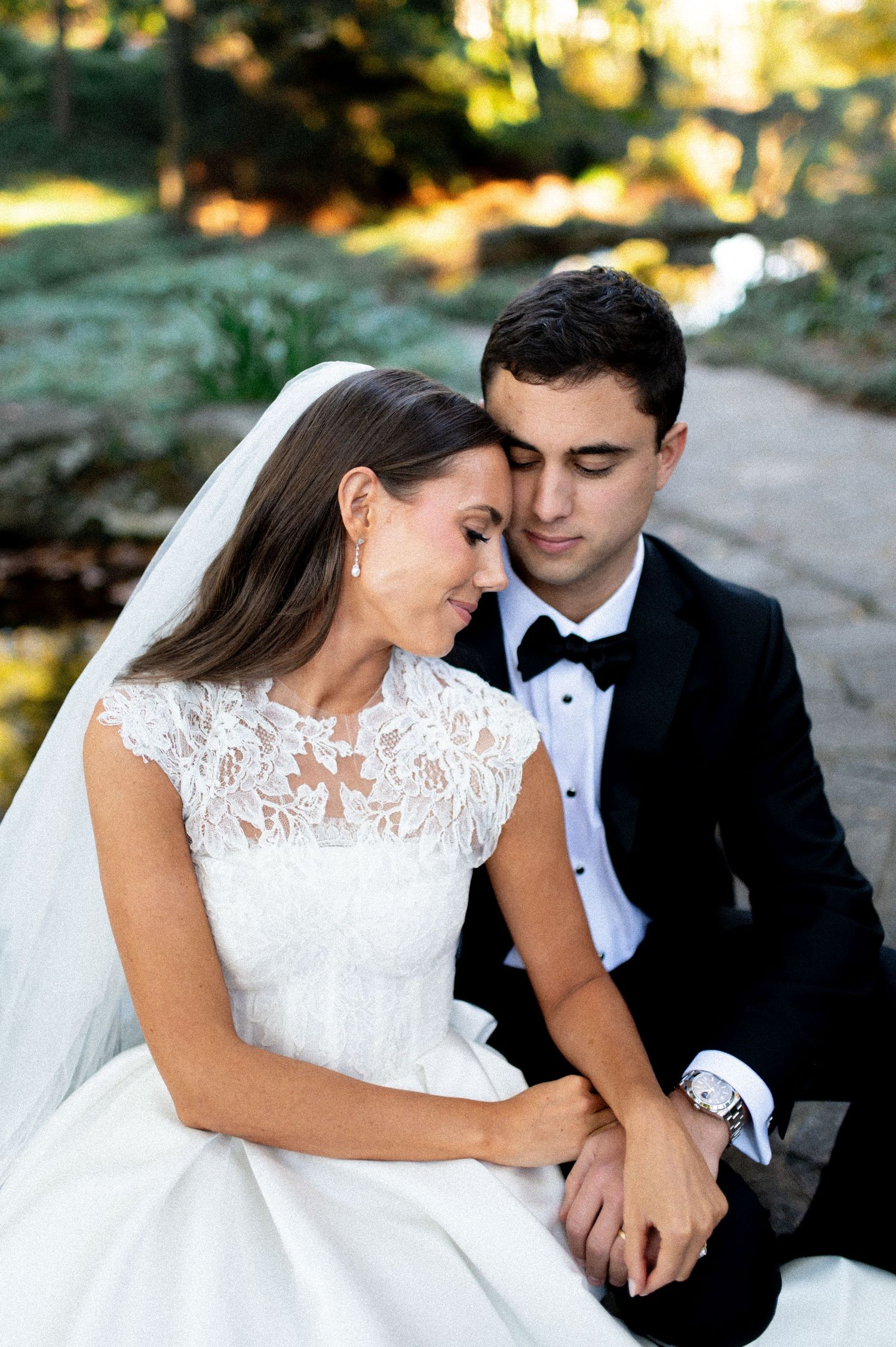 Romantic wedding portraits in soft sunlight with elegant white lace gown and formal attire.