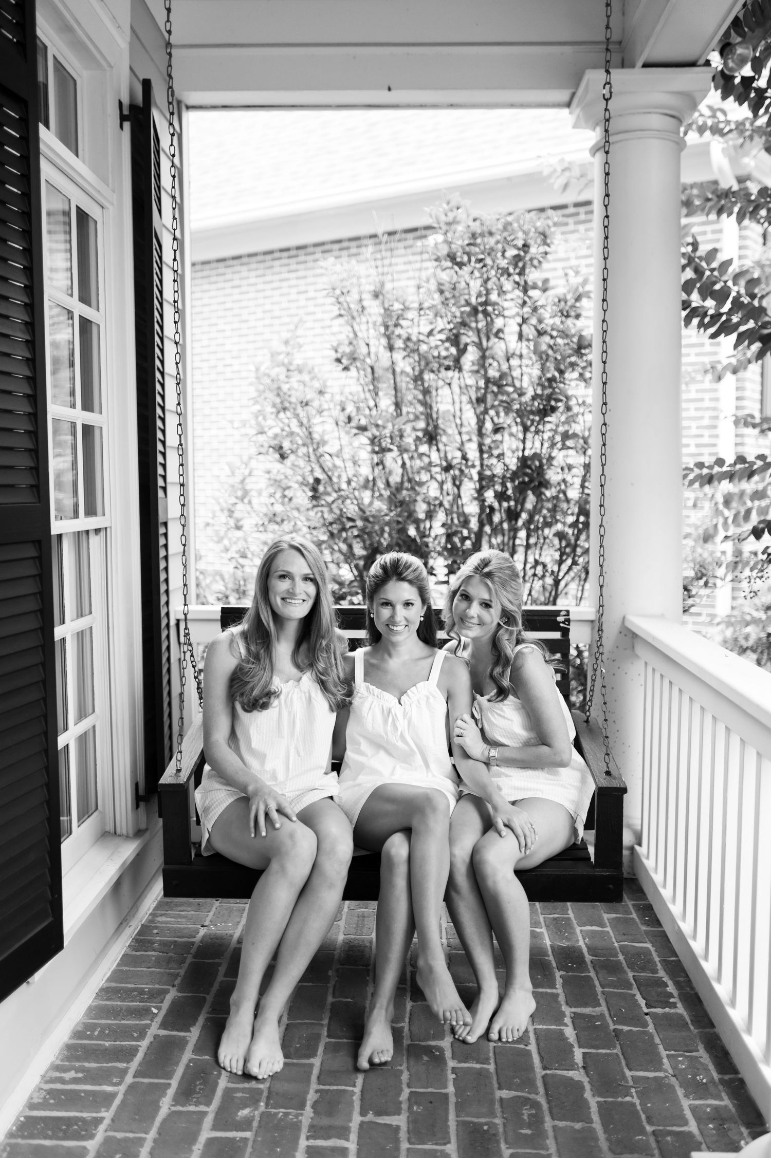Group relaxing on front porch swing in black and white photography.