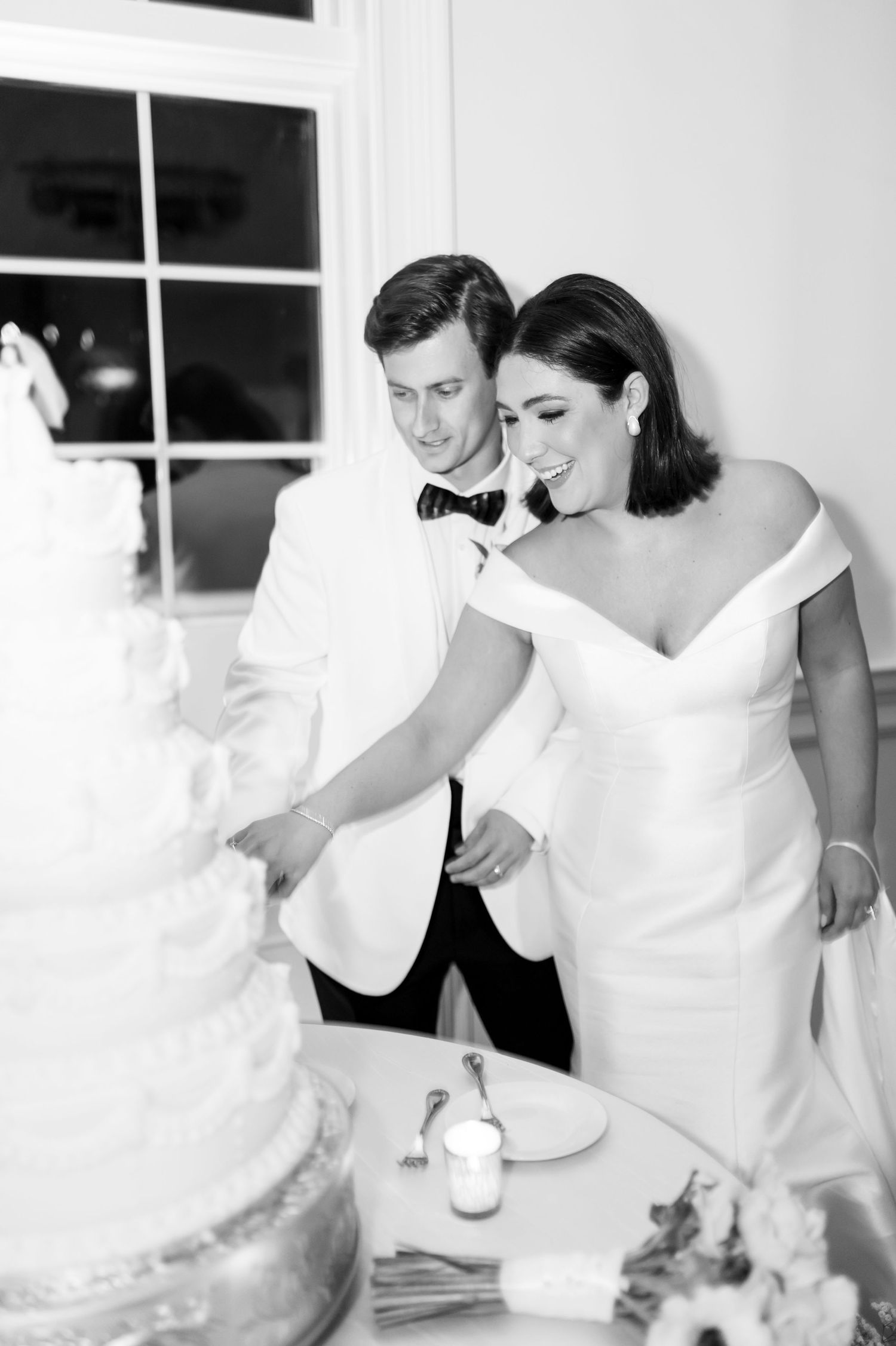 Intimate black and white wedding preparation moment in white interior.