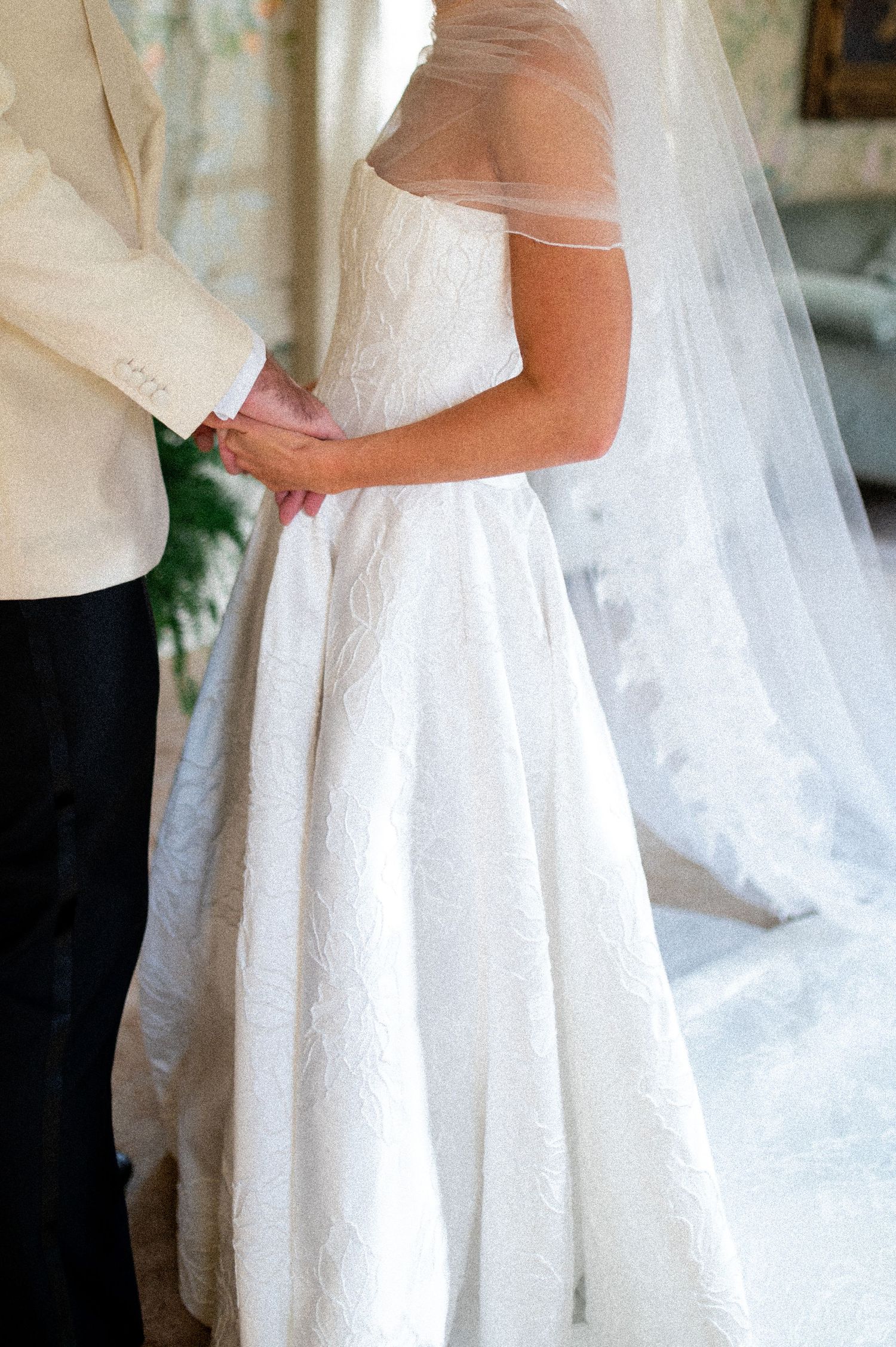 Close-up details of a white wedding dress with intricate fabric and flowing design.