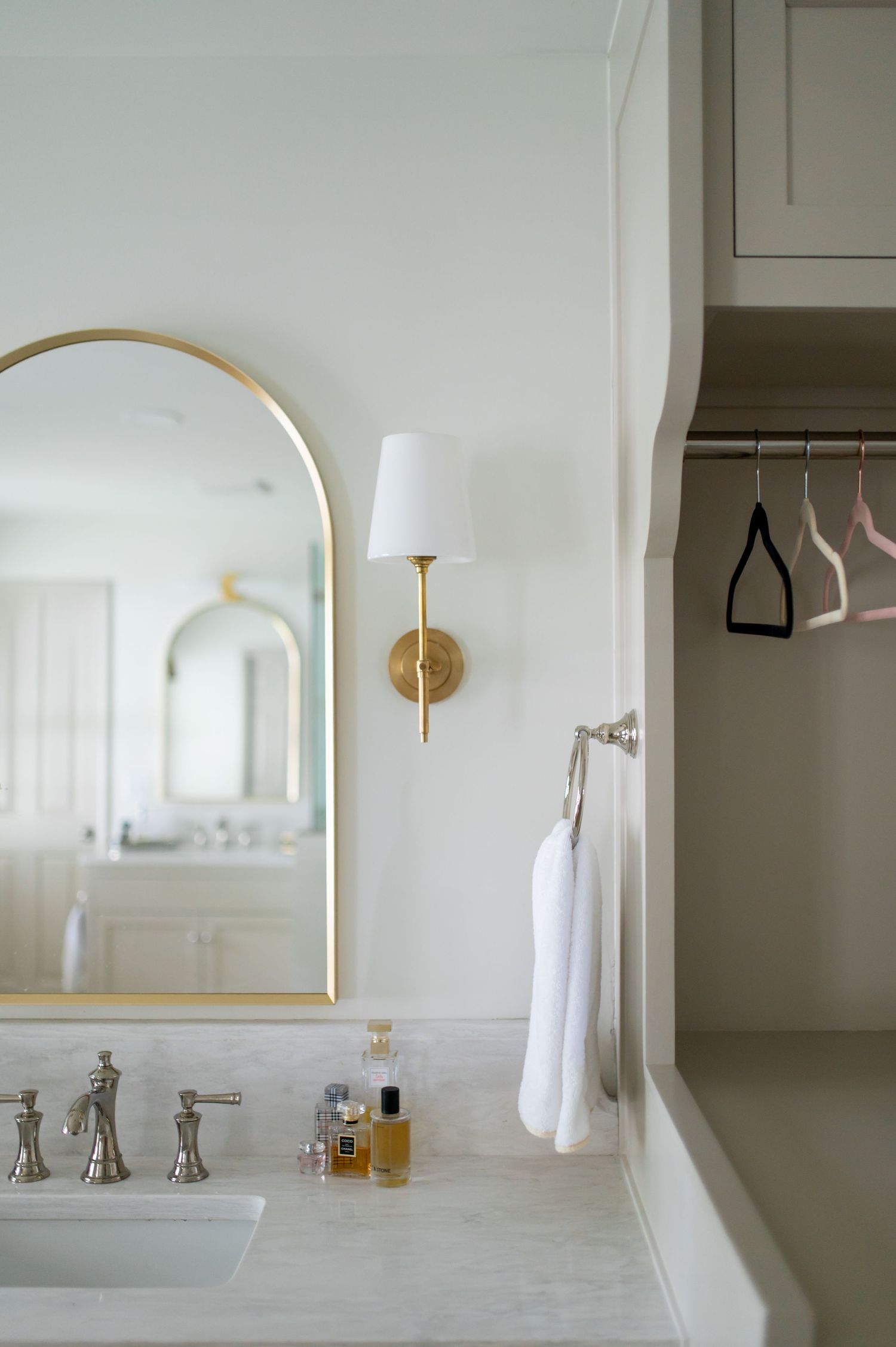 Minimalist bathroom vanity with gold fixtures, arched mirror, and white walls featuring a sleek modern design.