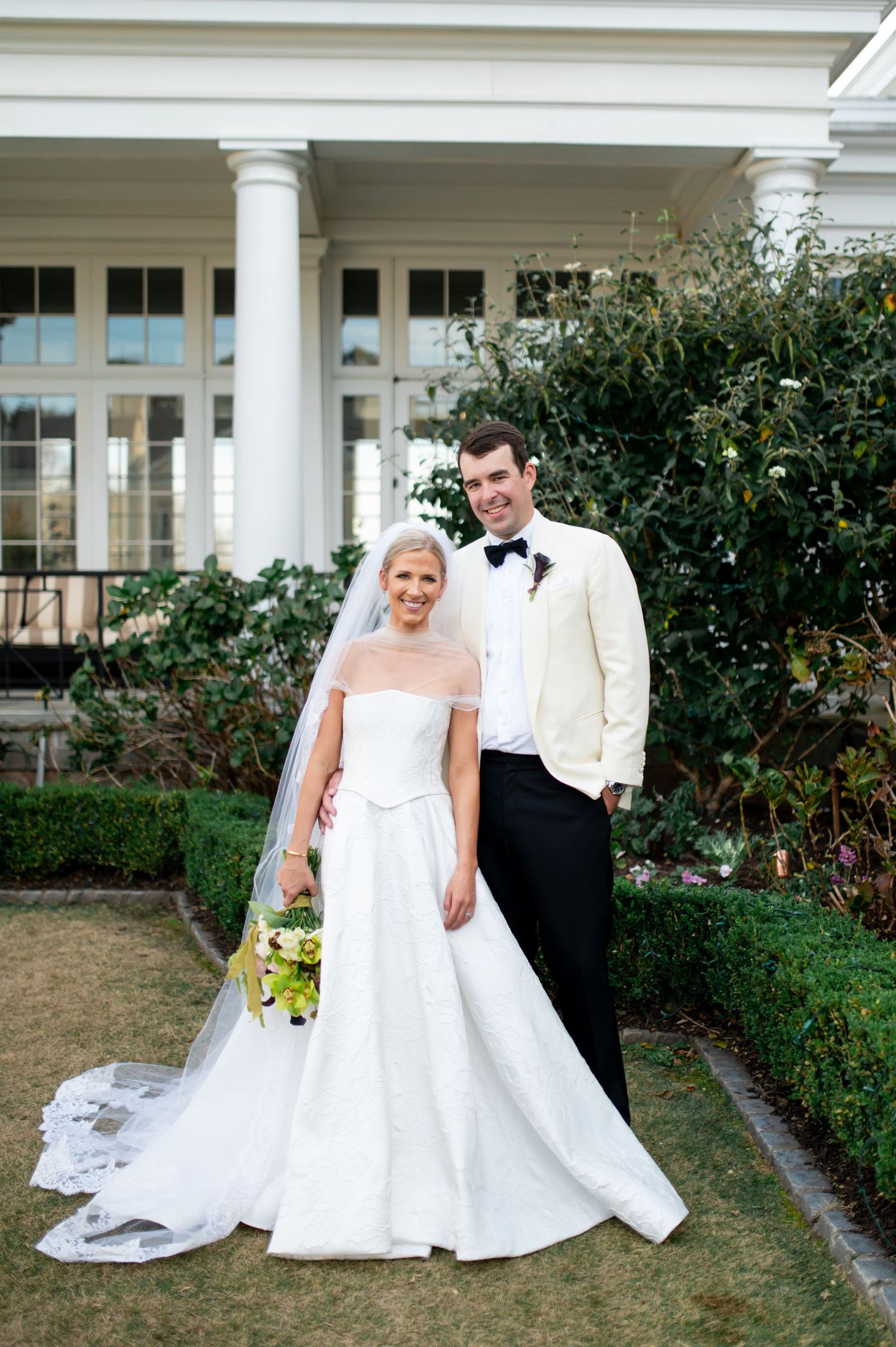 Wedding portraits featuring classic architecture and beautiful landscaping at an elegant venue.