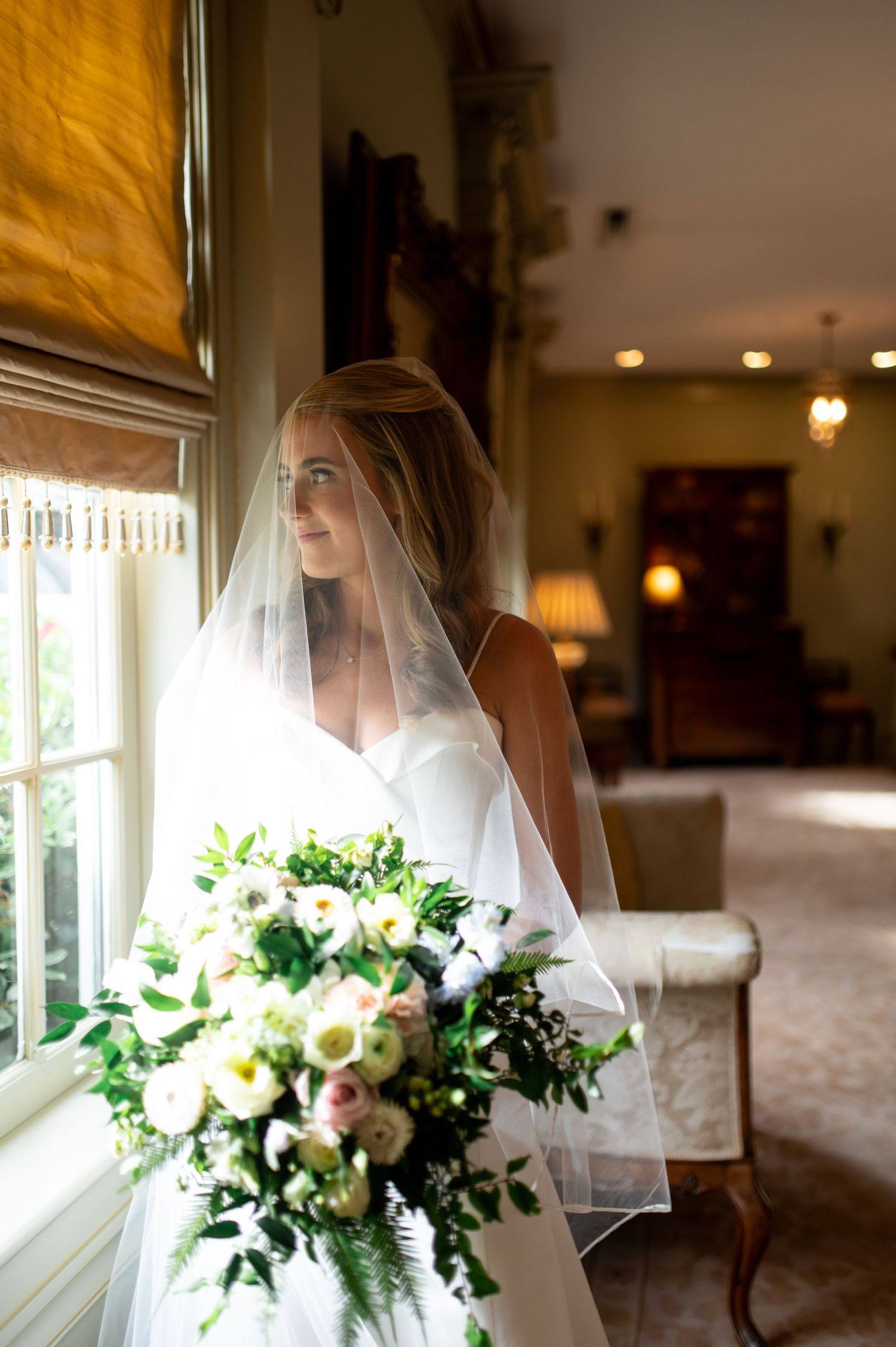 Artistic bridal portraits with soft window light and delicate floral bouquet.