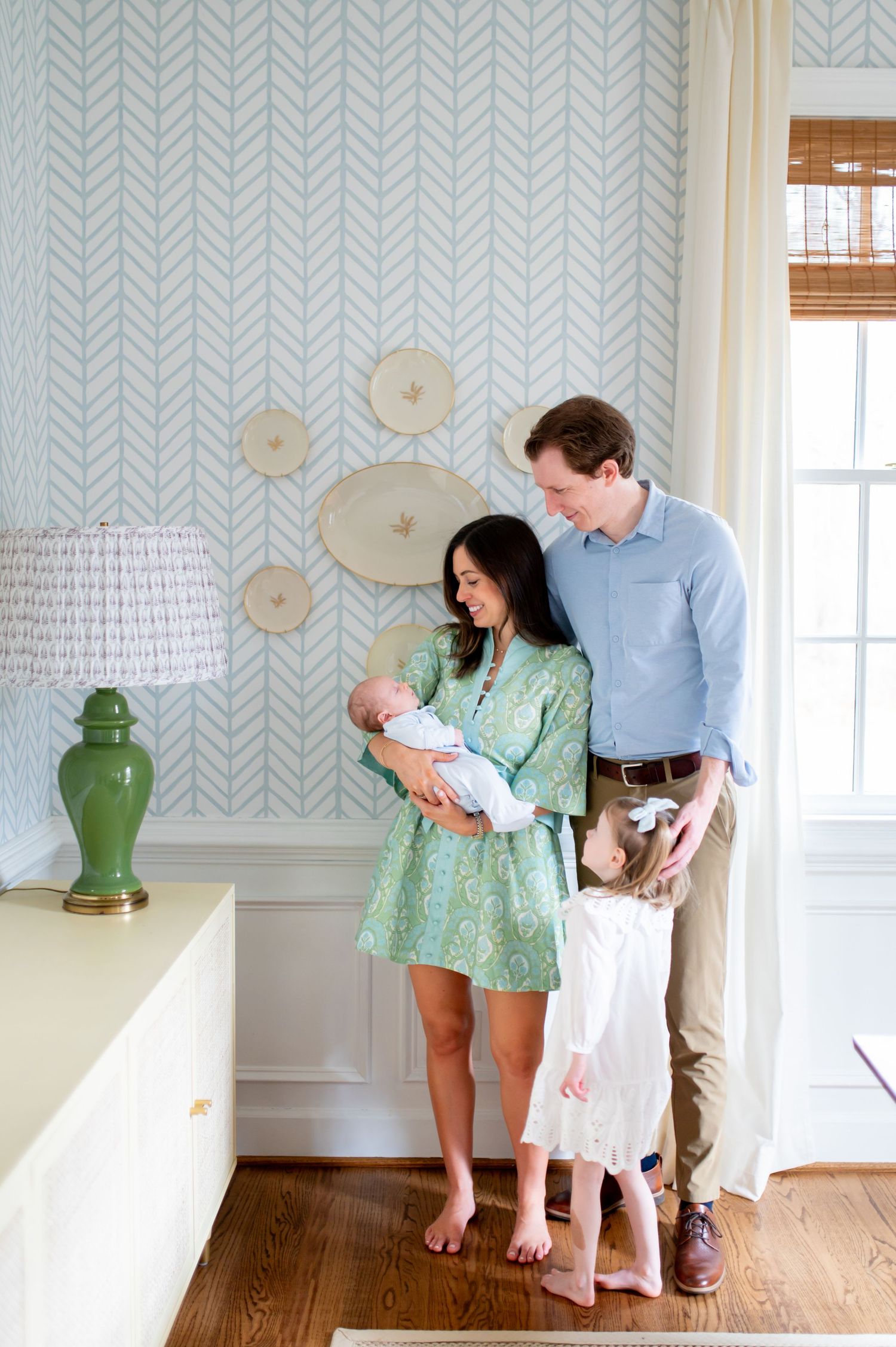 Family sharing tender moments in a bright room with herringbone wallpaper and hardwood floors.