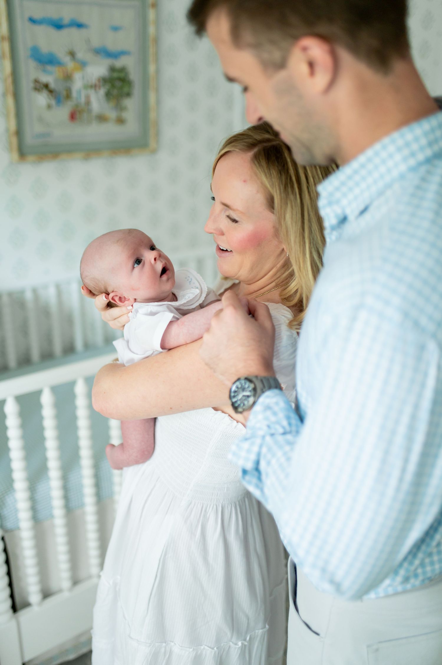 New parents lovingly holding their newborn baby in a softly decorated nursery room.