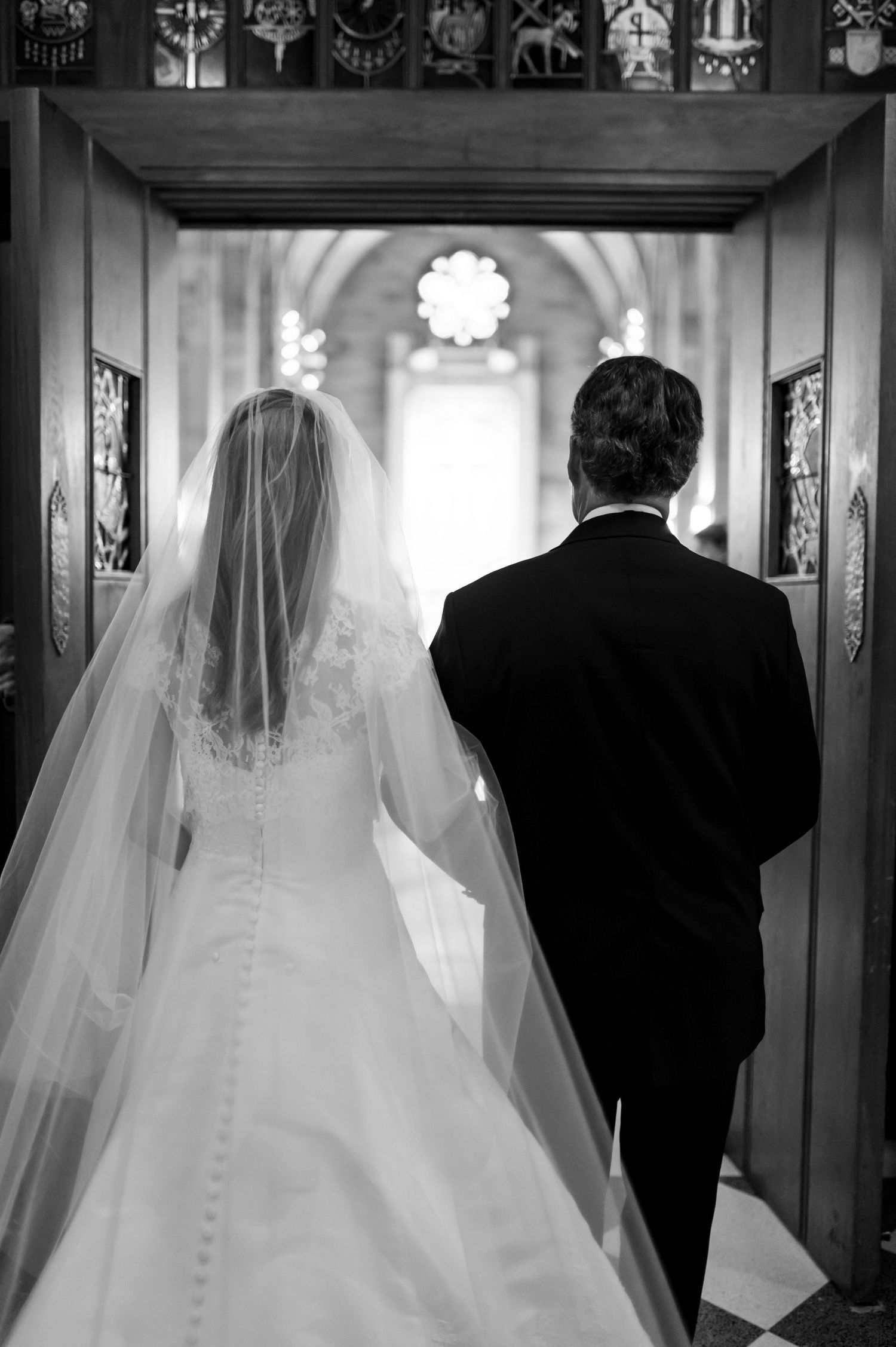 Black and white wedding processional photos in ornate church hallway.