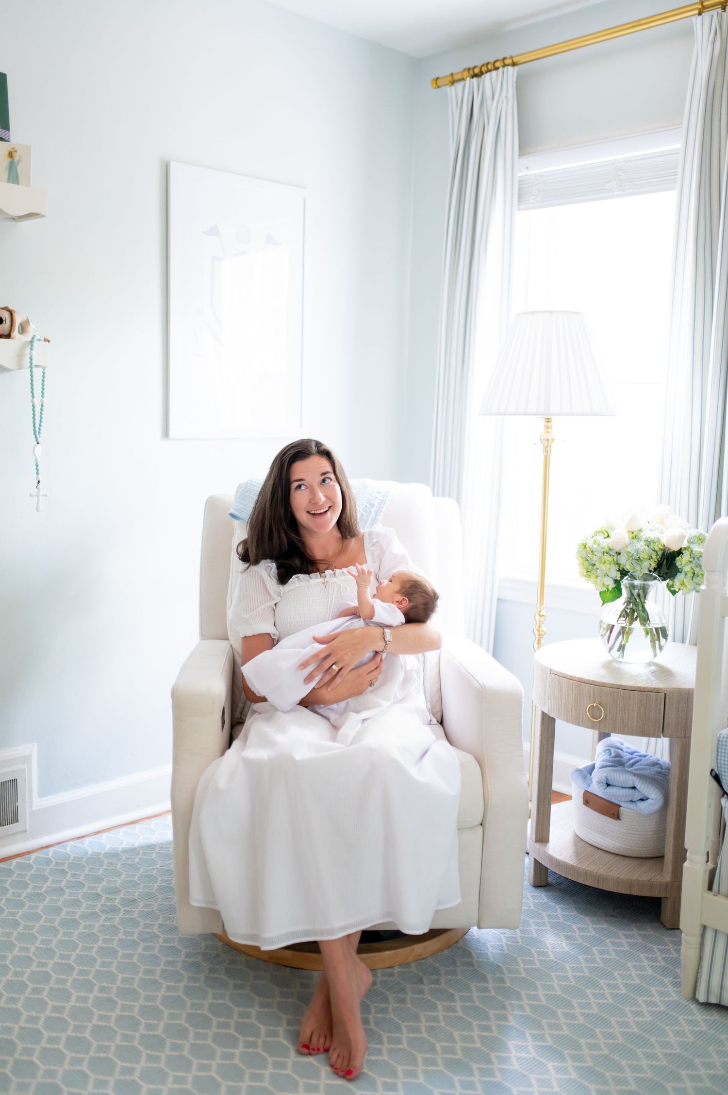 A bright nursery scene with a rocking chair, floral arrangement, and soft decor elements.