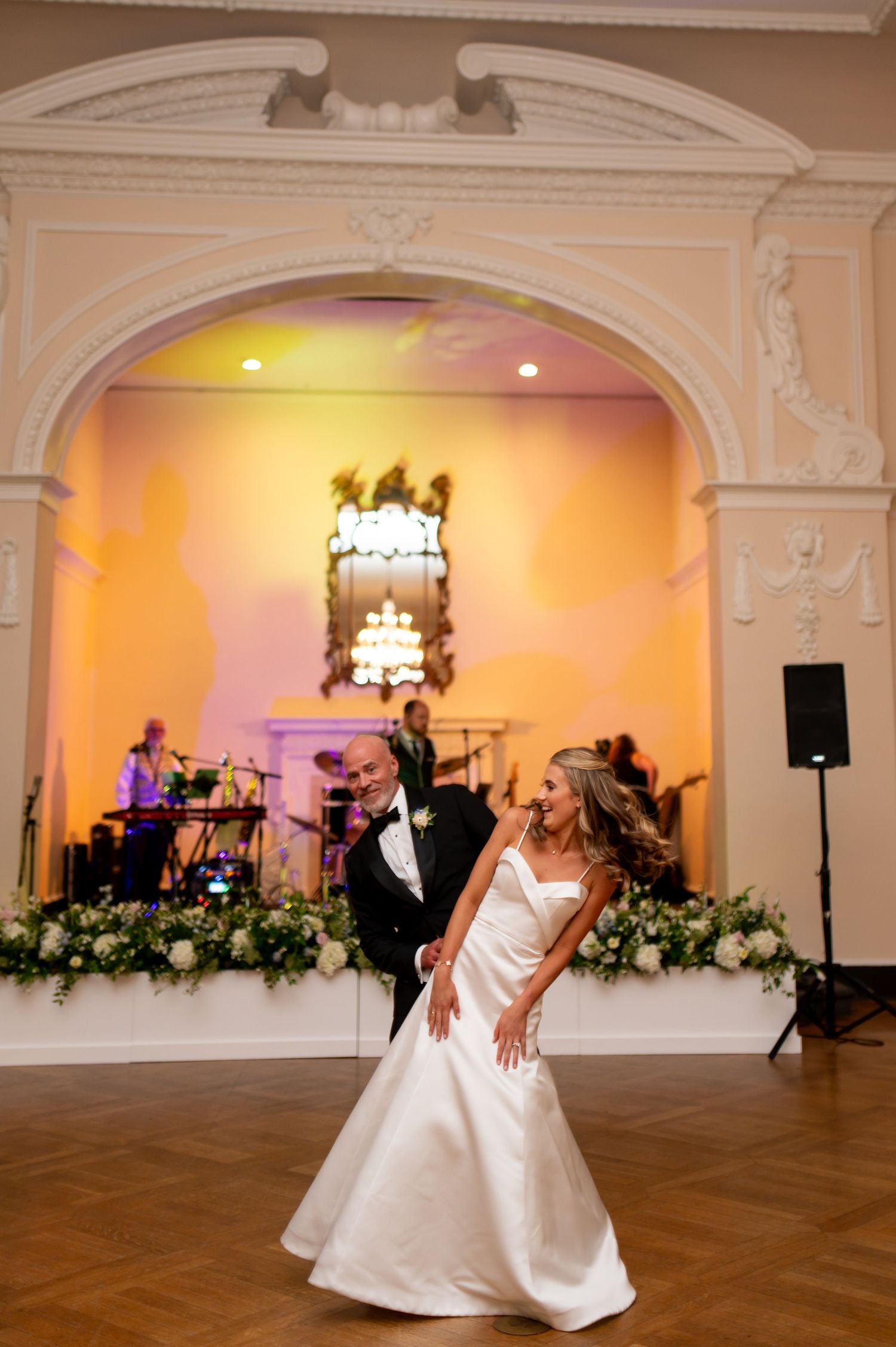 Wedding dance in an ornate ballroom with arched doorways and warm lighting.