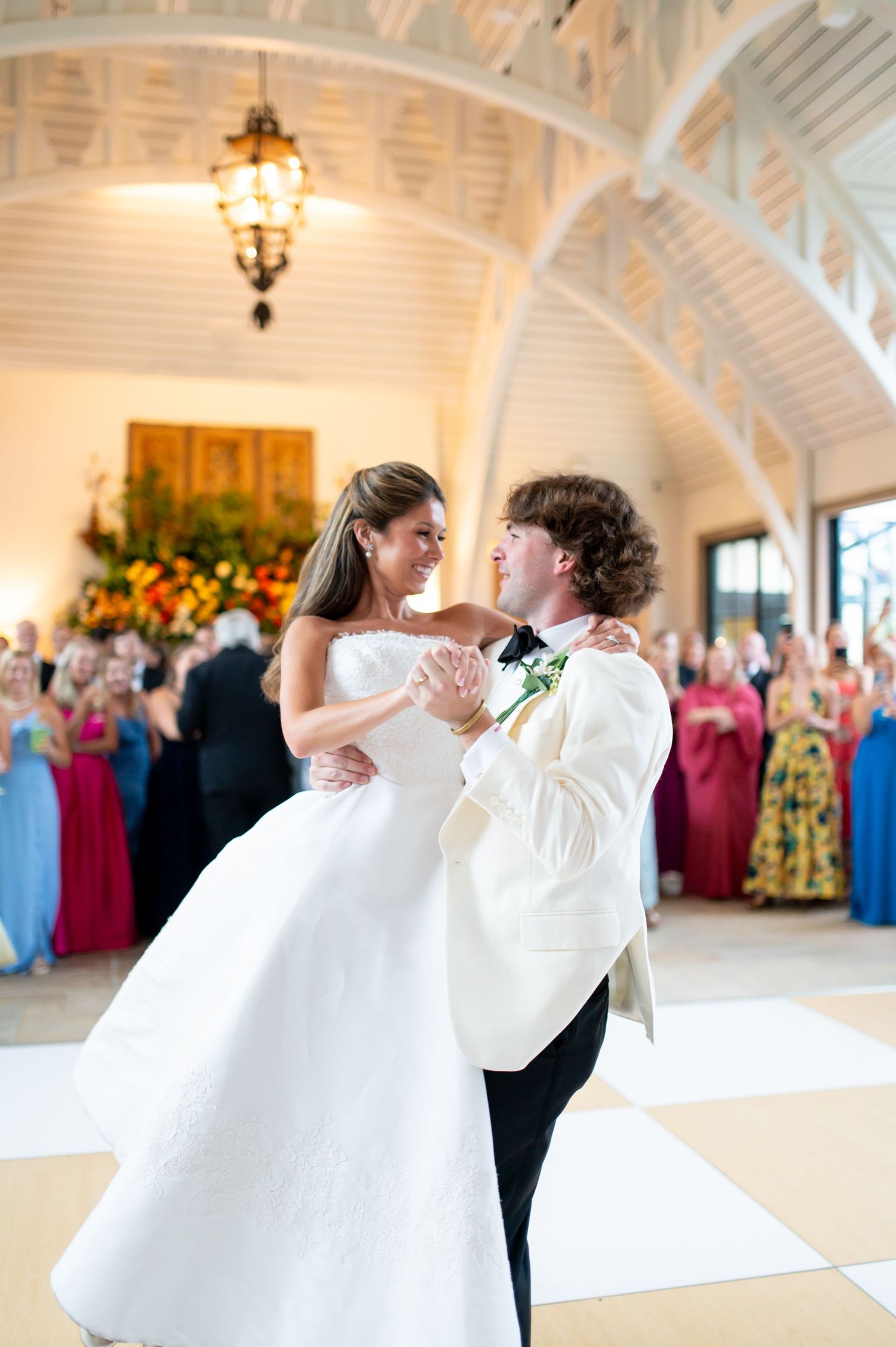 Couple shares intimate moment during first dance in elegant white-arched reception venue.