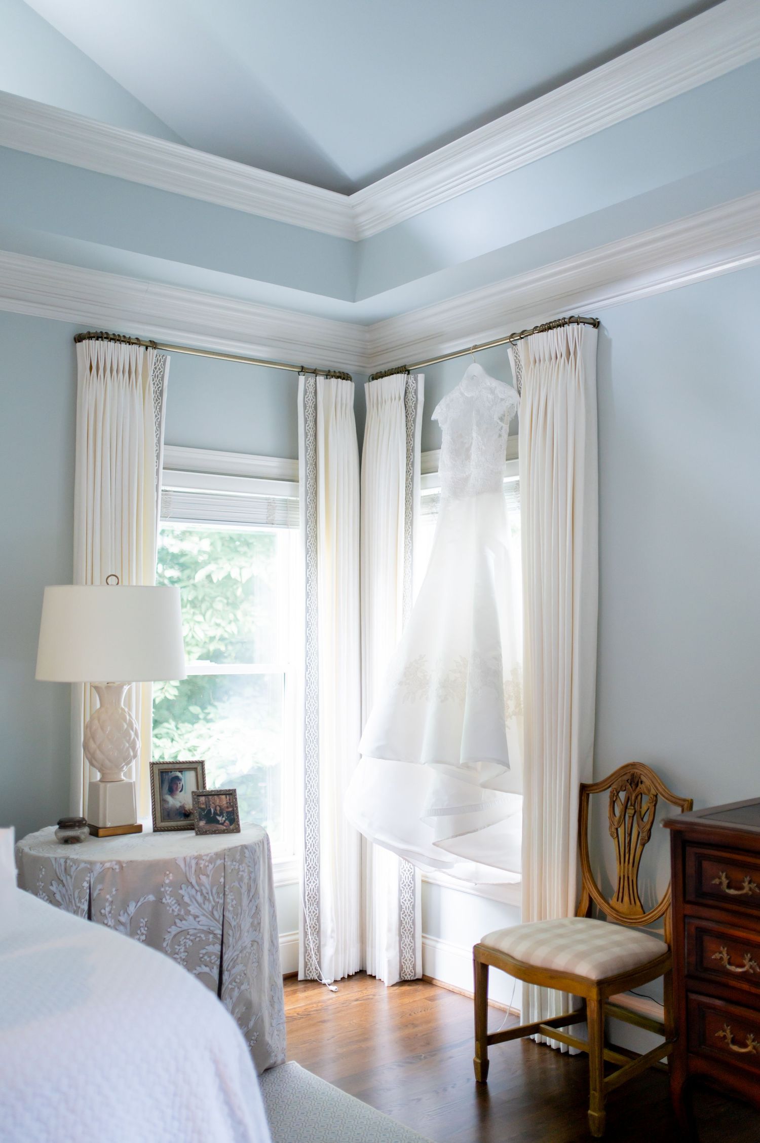 Elegant bedroom with pale blue walls, white curtains and classic furniture.