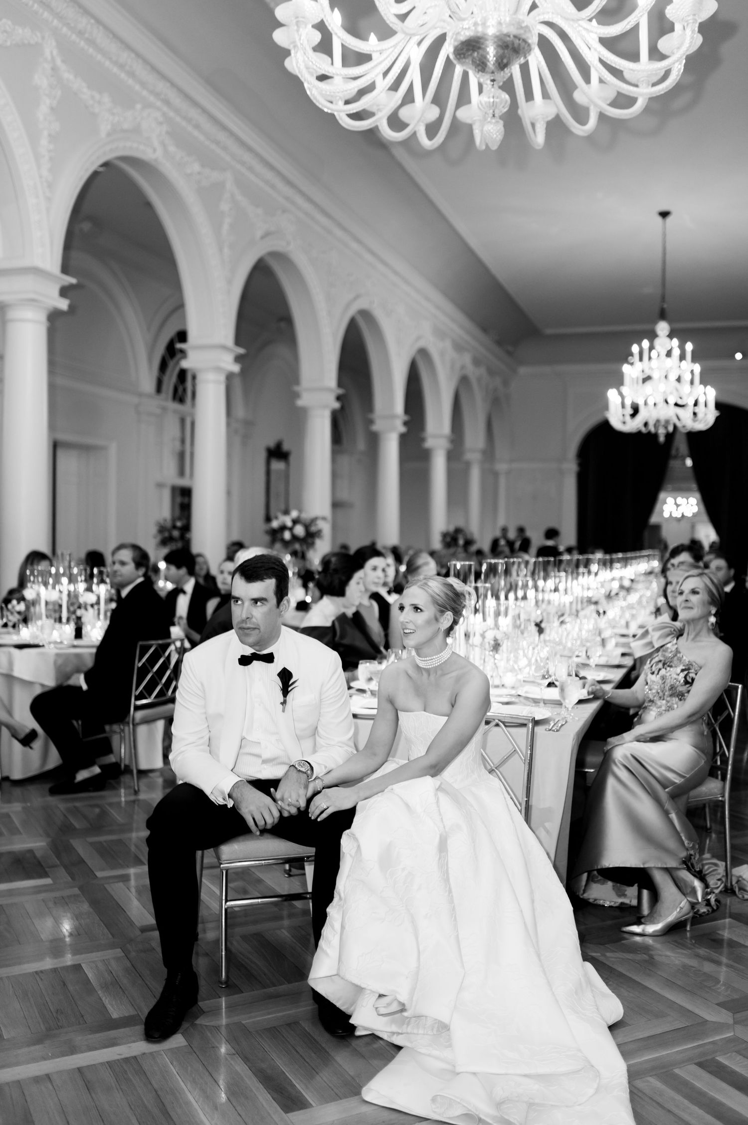 Black and white photos of wedding reception dancing in a grand ballroom with chandeliers.