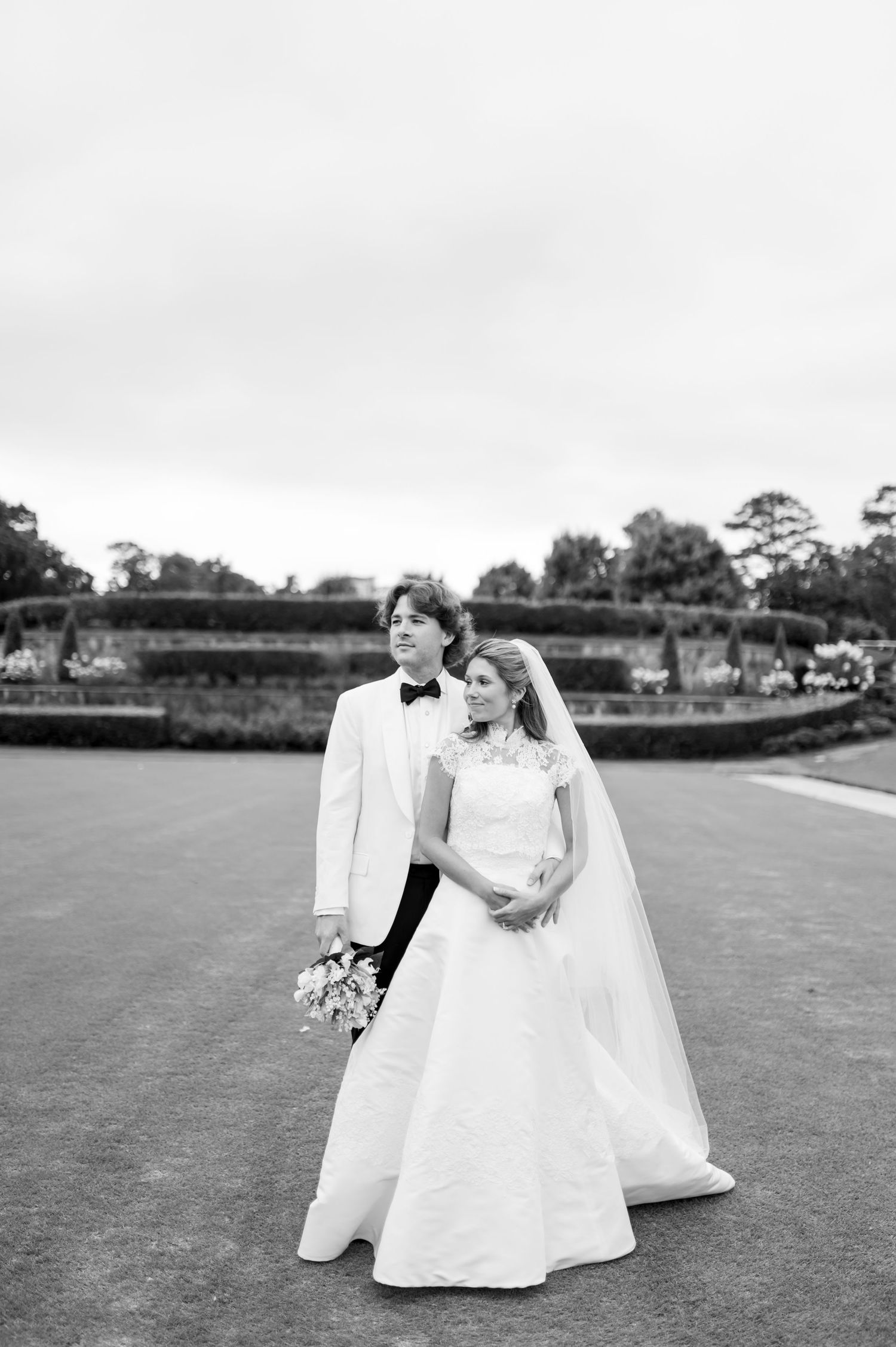 Black and white wedding portrait of couple dancing on an expansive lawn.
