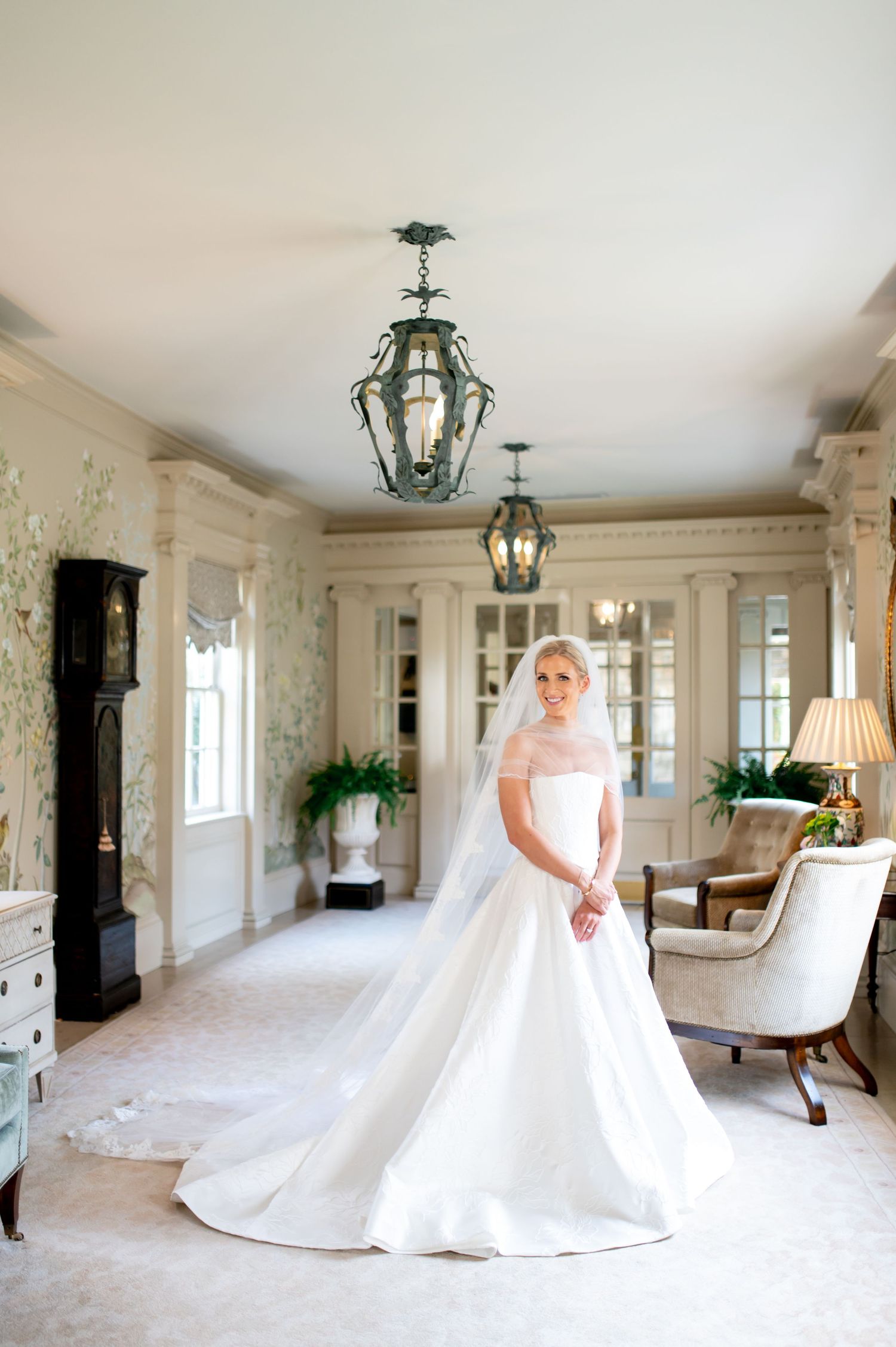 Panoramic view of a bride in a ballgown in an elegant white room with hanging lanterns.