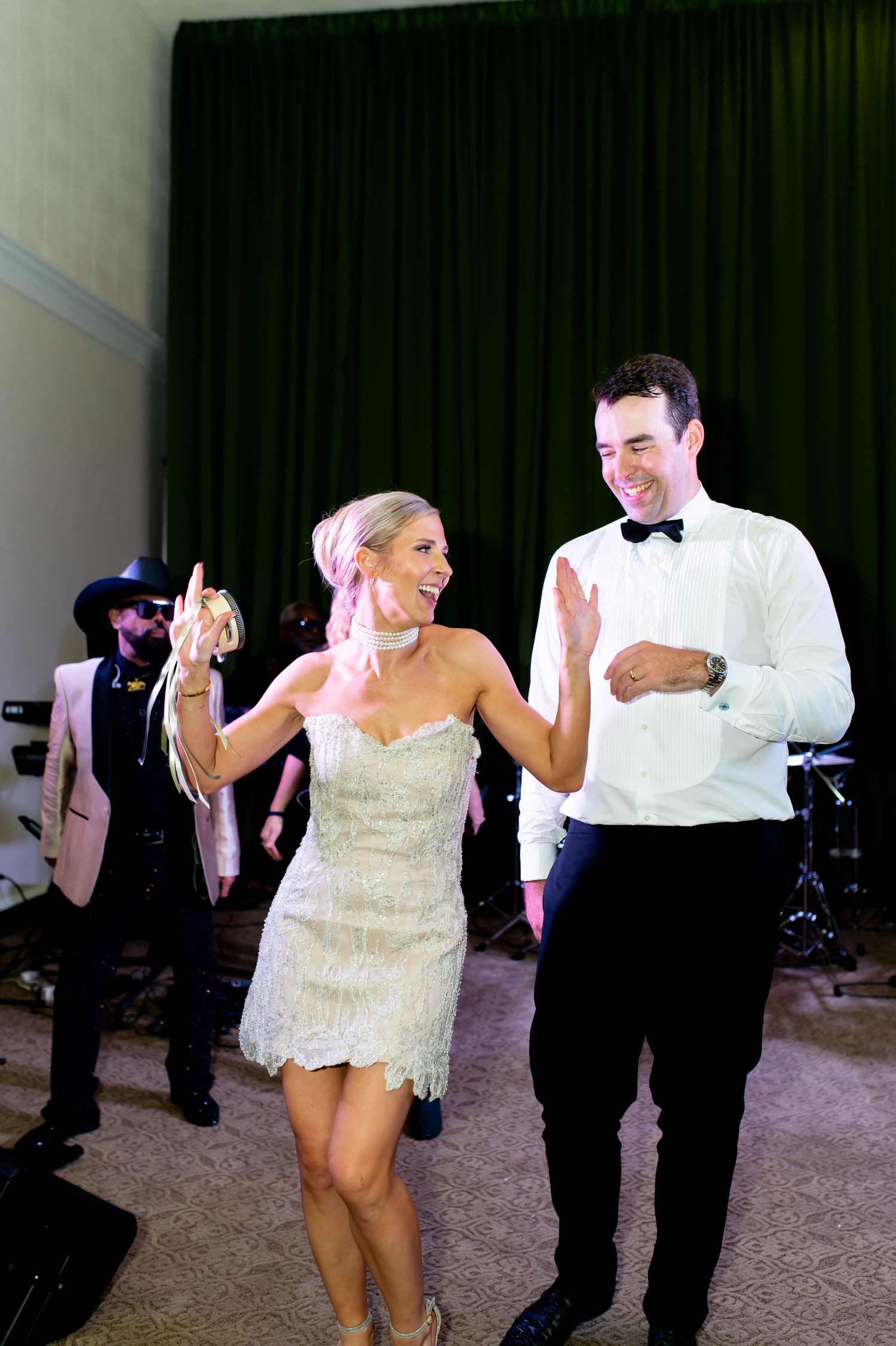 Wedding couple and guests dancing energetically at indoor reception.
