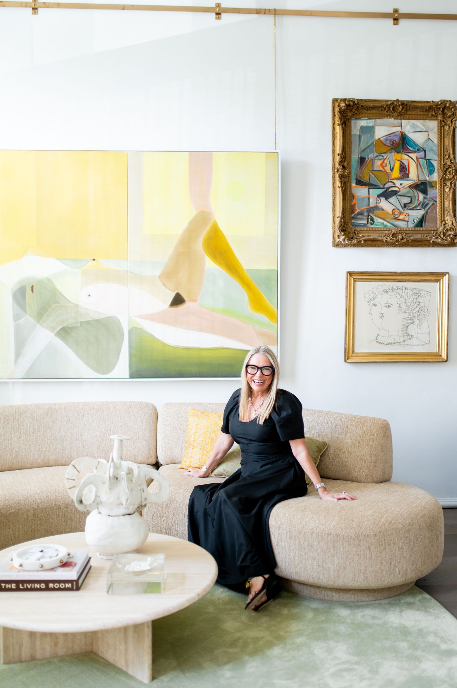 Modern art gallery interior with curved beige sofa and framed artwork on white walls.