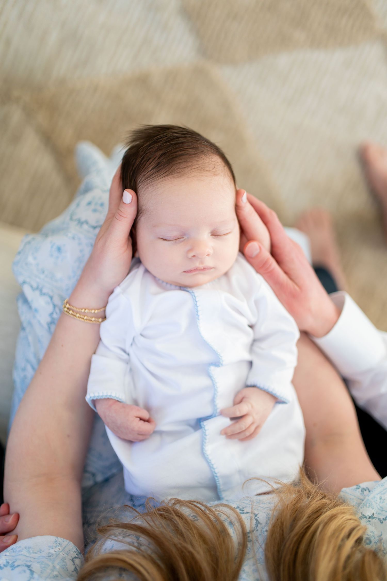 A sleeping newborn baby wearing white clothing rests peacefully on a light blue blanket.