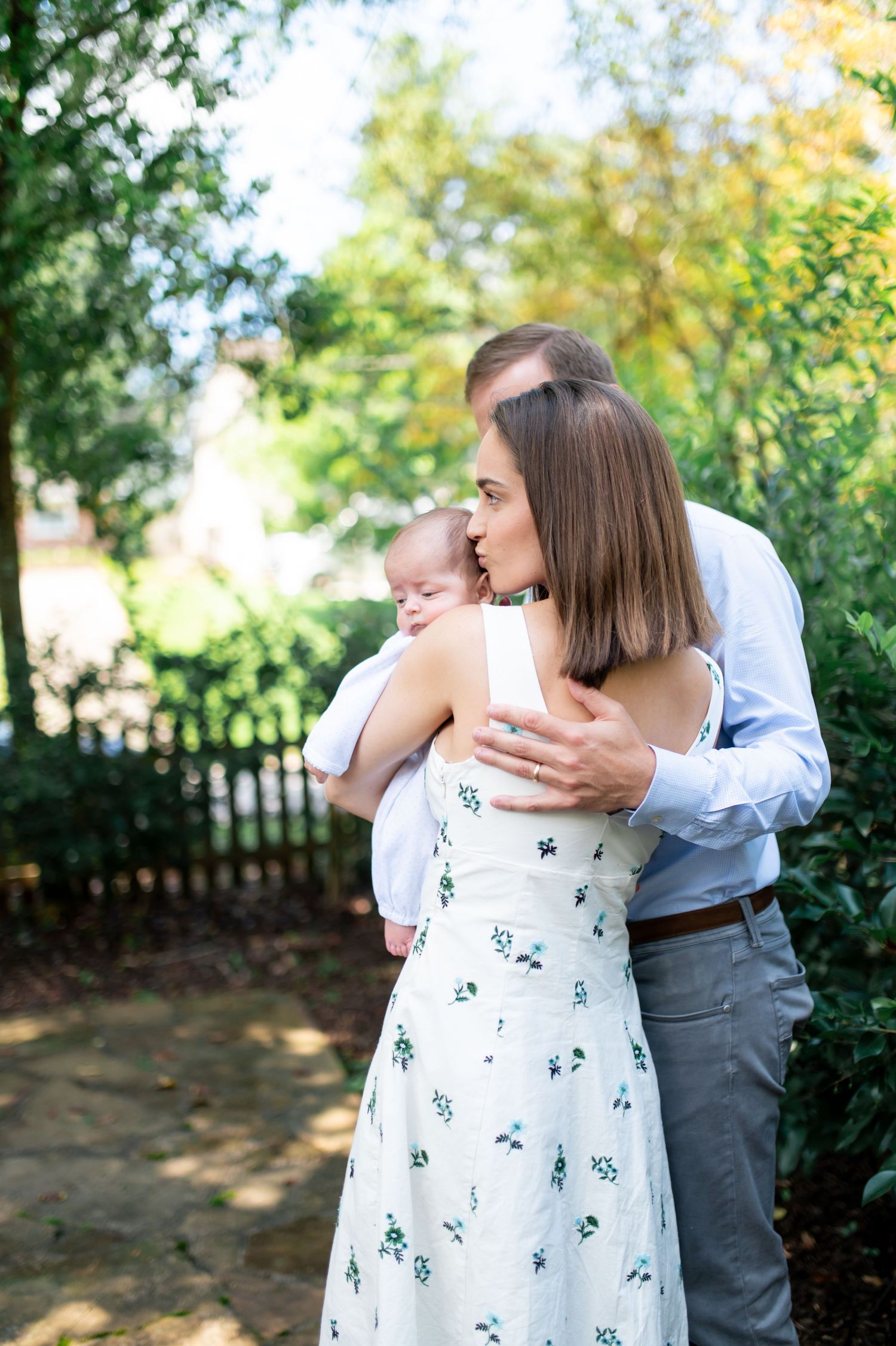 Family portrait session in a garden setting with autumn trees in the background.