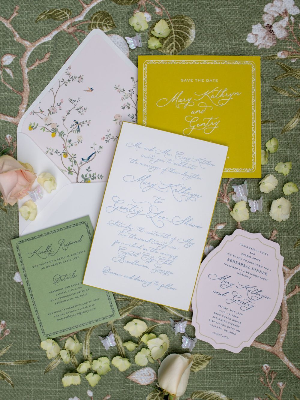 Elegant wedding invitation suite with yellow save-the-date, white invite, green RSVP card, and floral envelope liner on sage background.