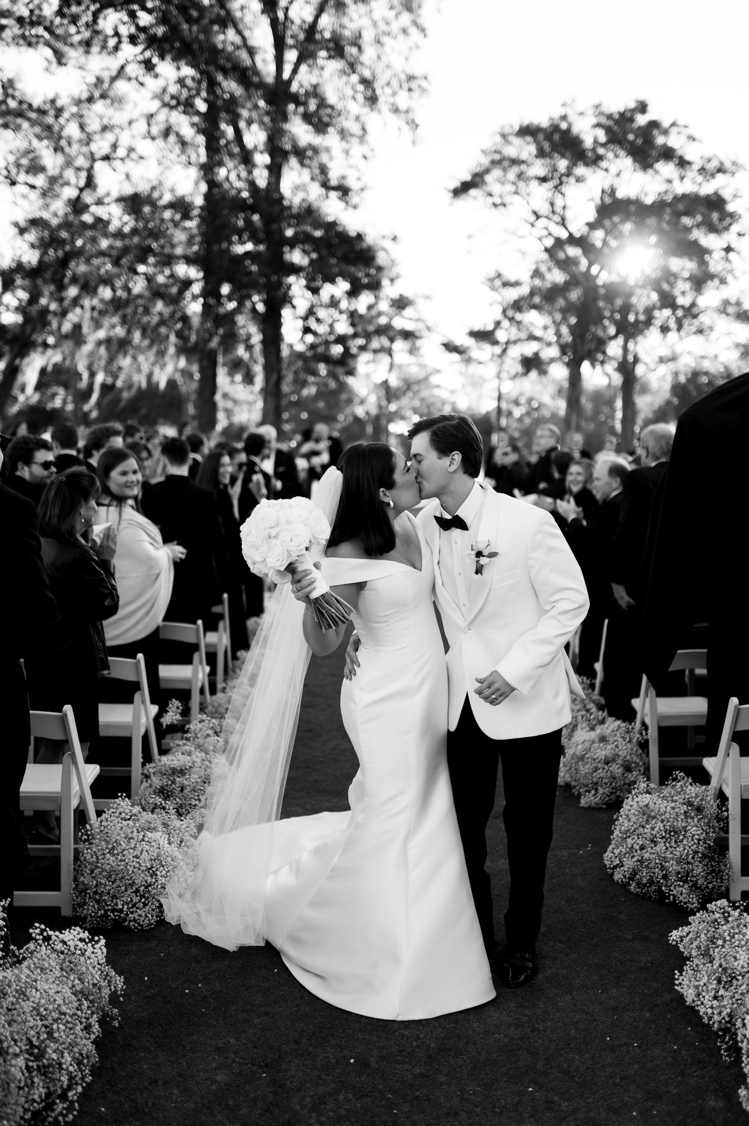 Black and white photo capturing a celebratory moment during an outdoor wedding ceremony.