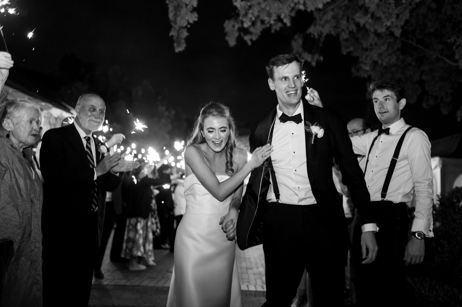 Nighttime sparkler exit celebration at formal event.
