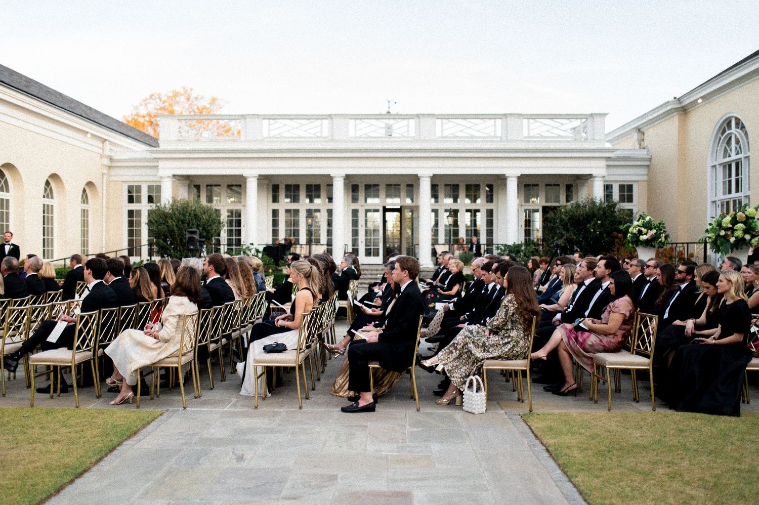 Outdoor wedding reception setup with rows of tables and chairs on a patio.