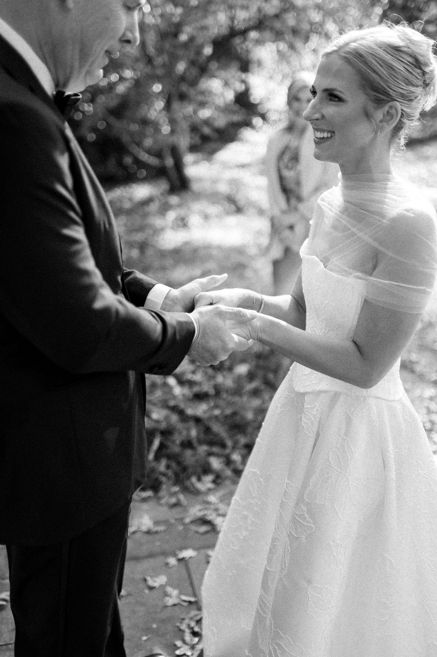Black and white capture of intimate ring exchange moment during wedding ceremony.