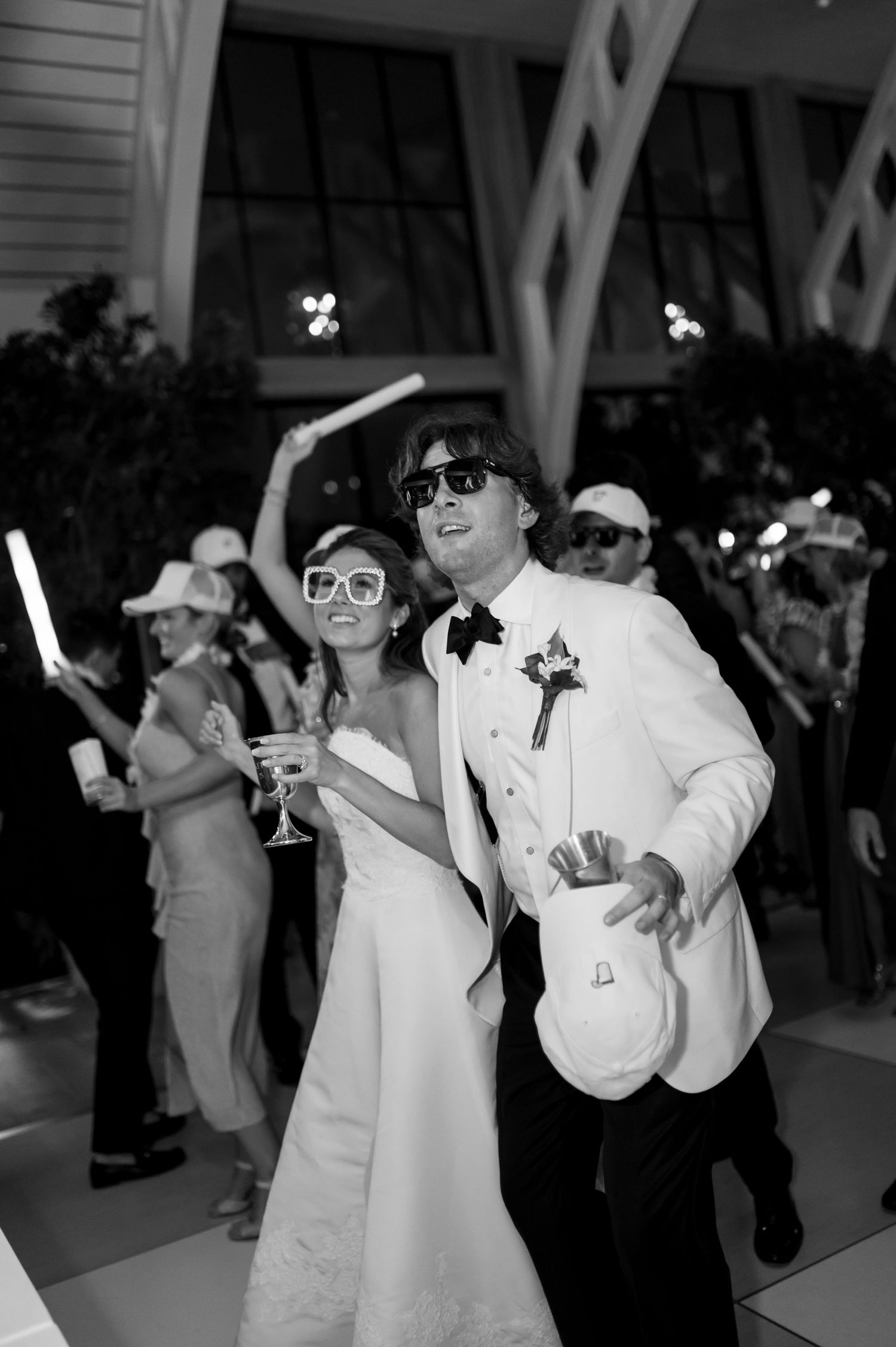 Wedding couple wearing sunglasses dance with glow sticks at their reception.