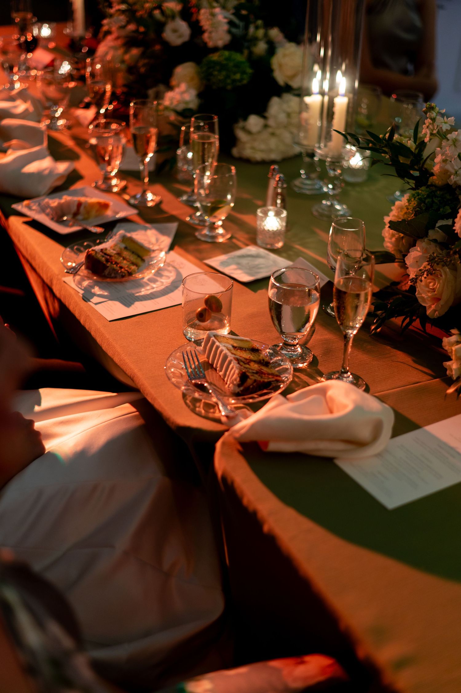 Elegant wedding reception table settings with glassware and warm ambient lighting.