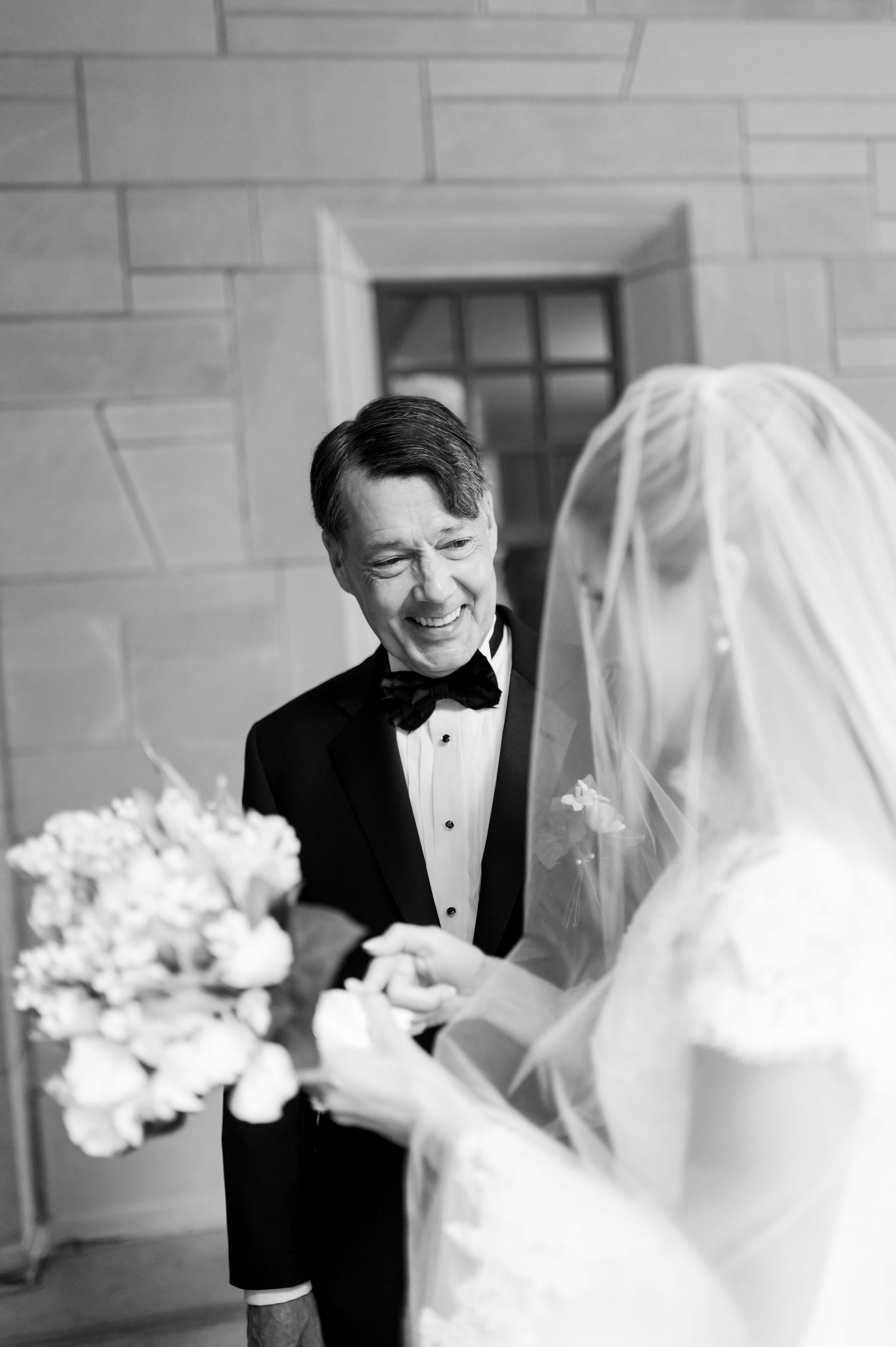 Emotional wedding moment captured in black and white with formal attire and white bouquet.