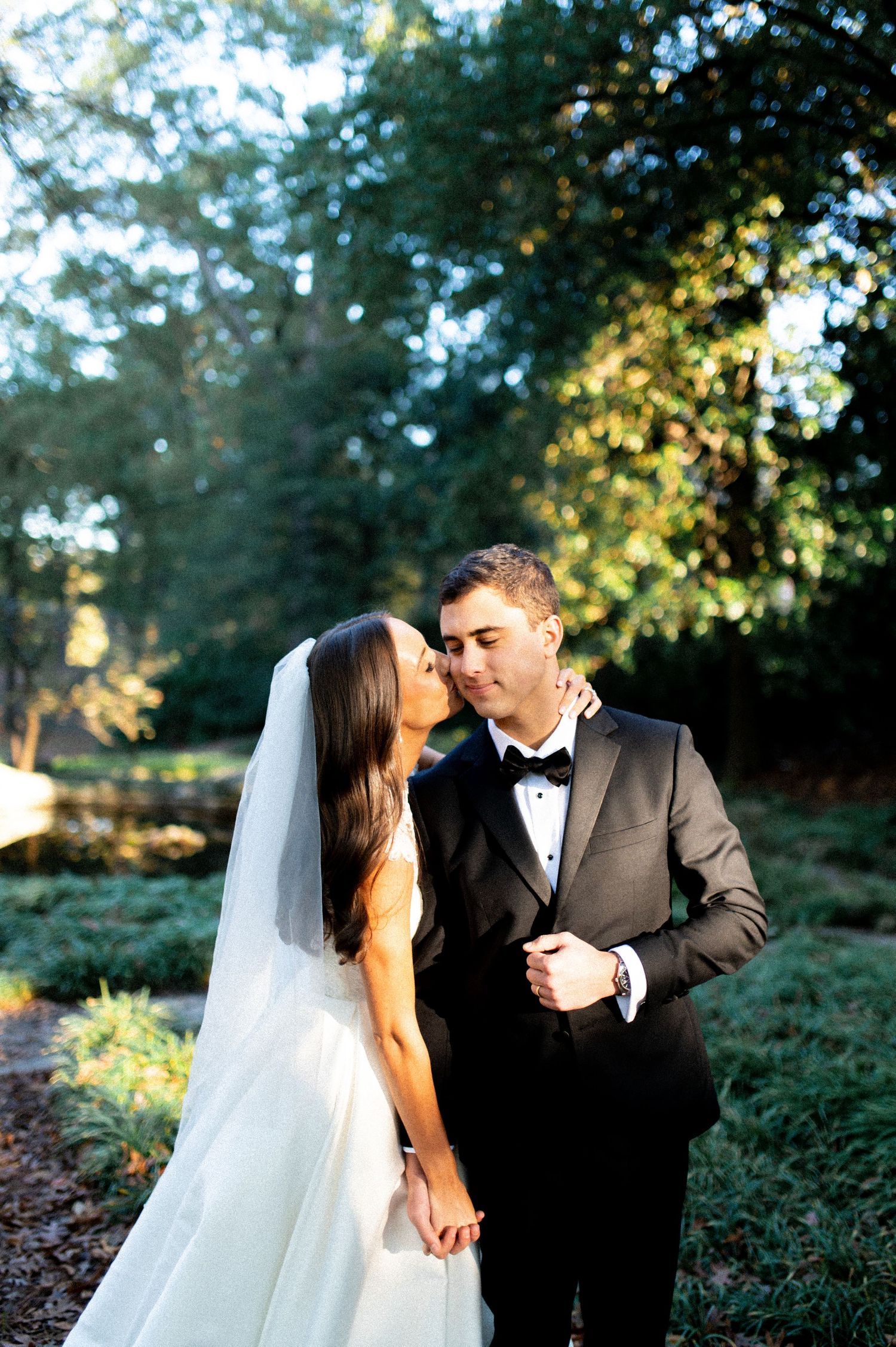 Romantic wedding couple shares intimate moments in a garden setting at sunset.