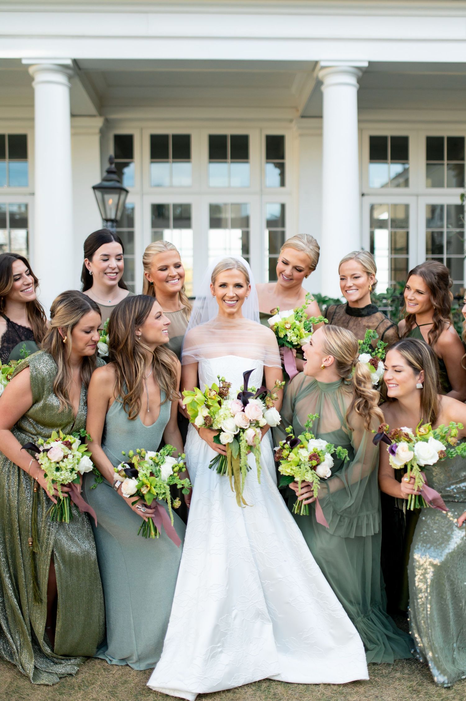Bridesmaids in sage dresses share joyful moment with bride in white gown.
