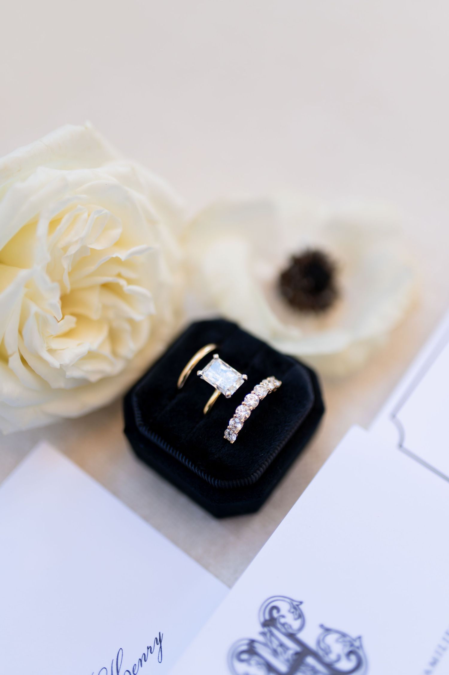Elegant engagement ring displayed in black velvet box with white roses.